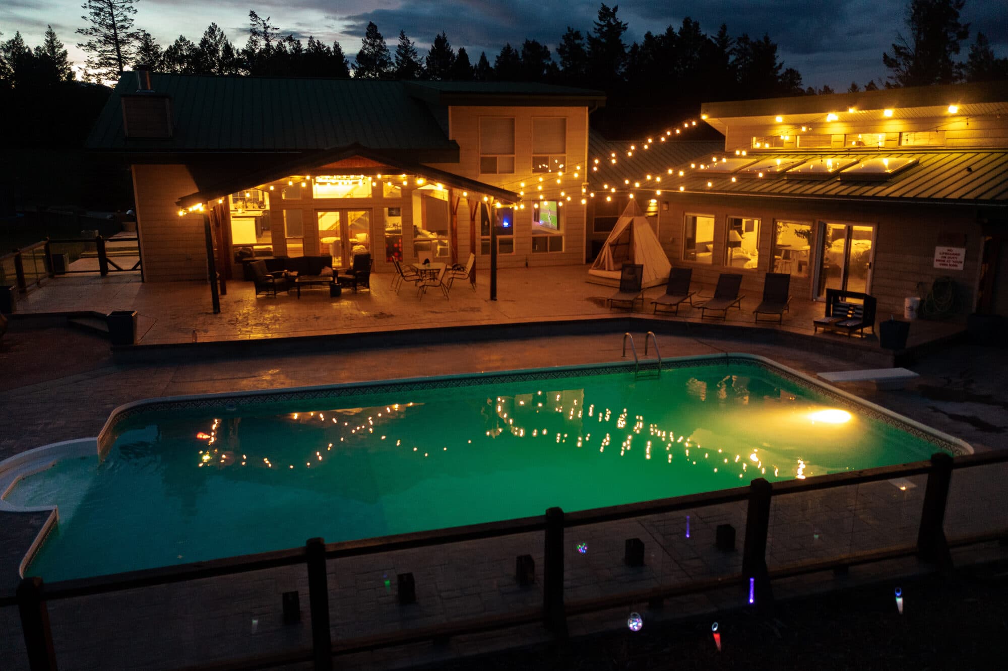 Reimagine Ranch heated pool and pool house lit at night