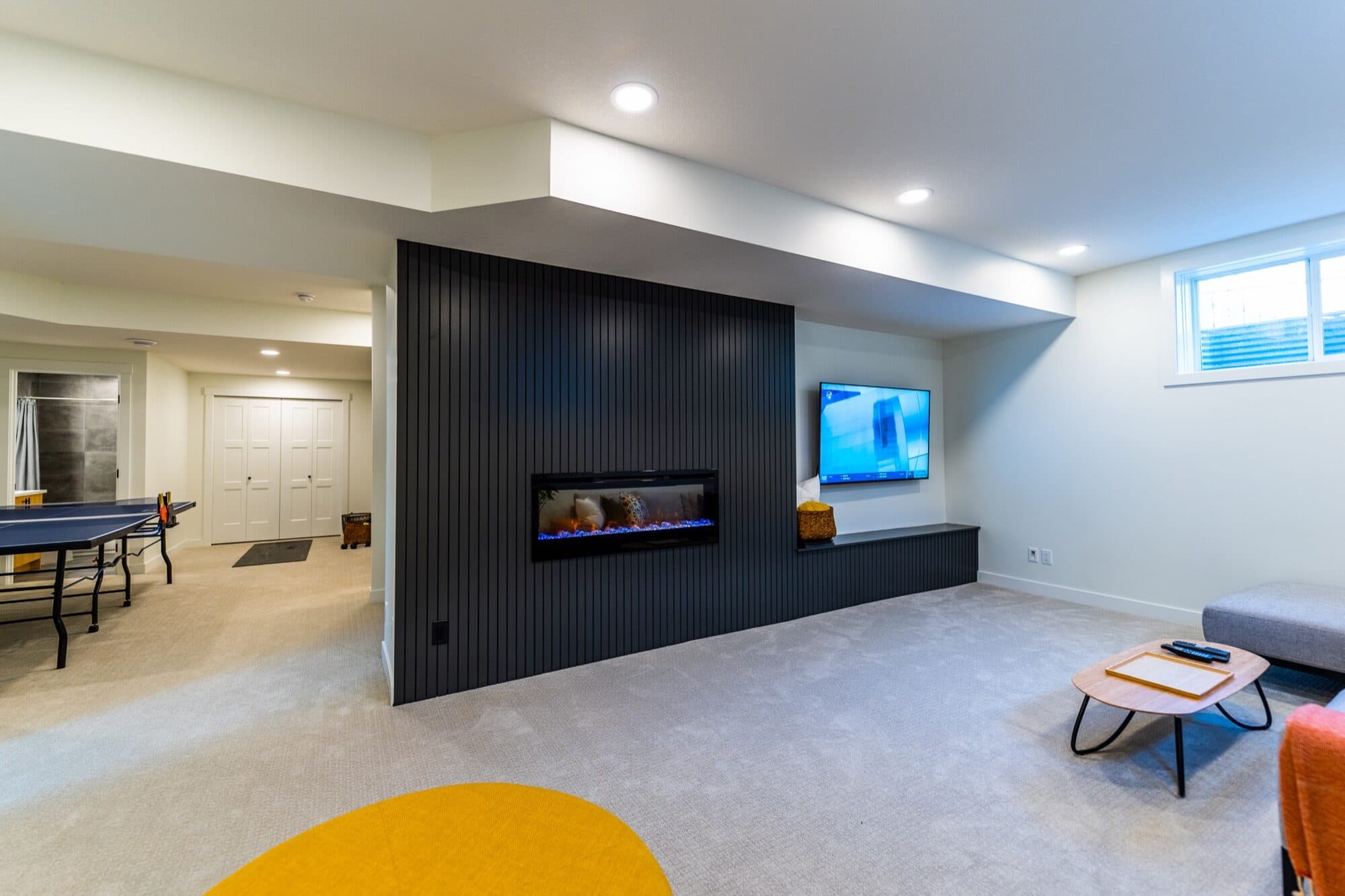 Basement games room with a black slat fireplace wall and a ping-pong table