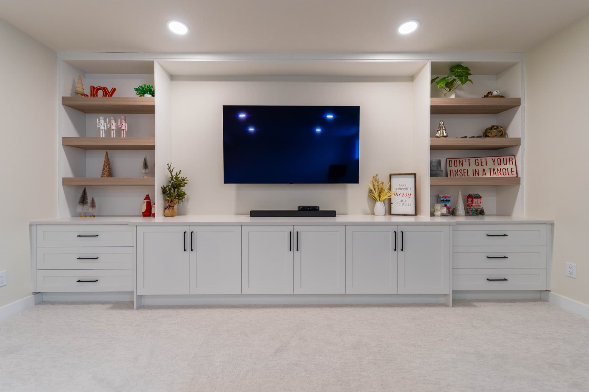 Bright basement media wall with white built-in cabinetry and floating shelves