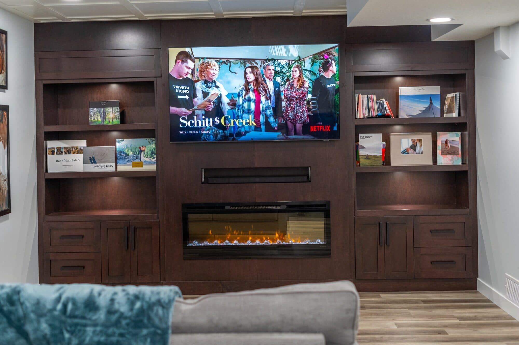 Finished basement media wall with dark wood built-ins and a linear fireplace by ReImagine Builders