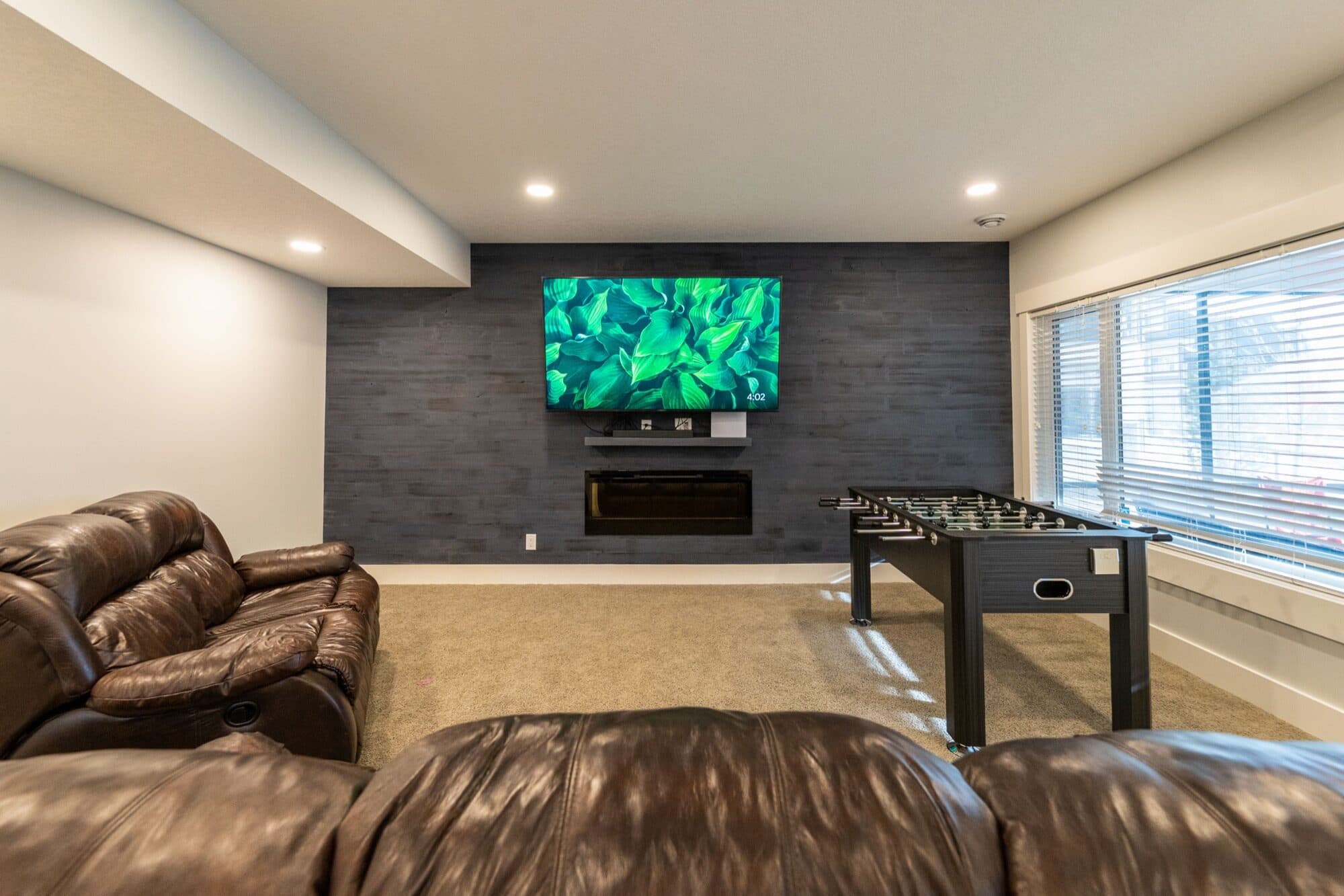 Basement lounge with a charcoal feature wall, foosball and leather recliners