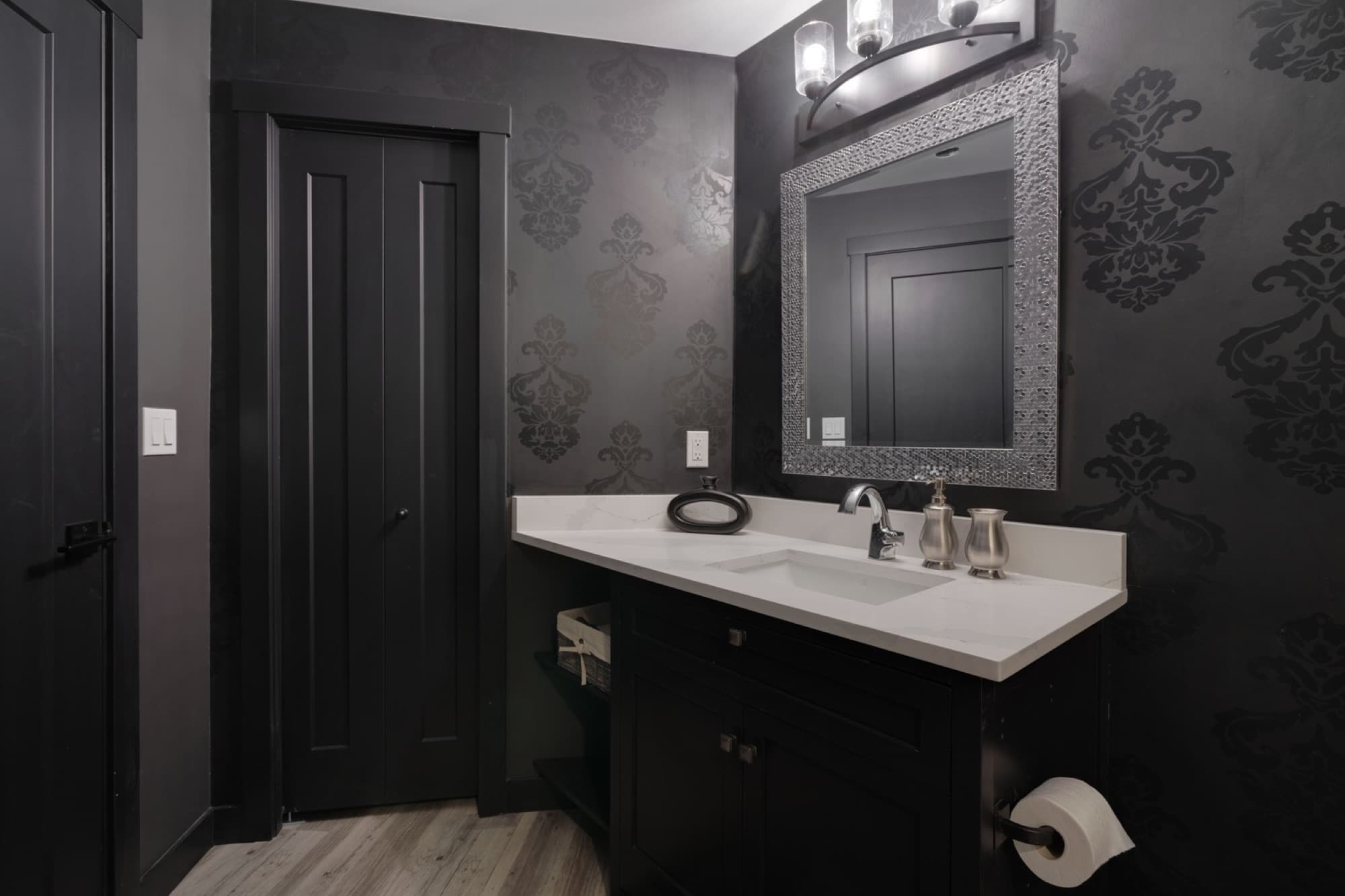 Dramatic basement bathroom with black damask wallpaper and vanity