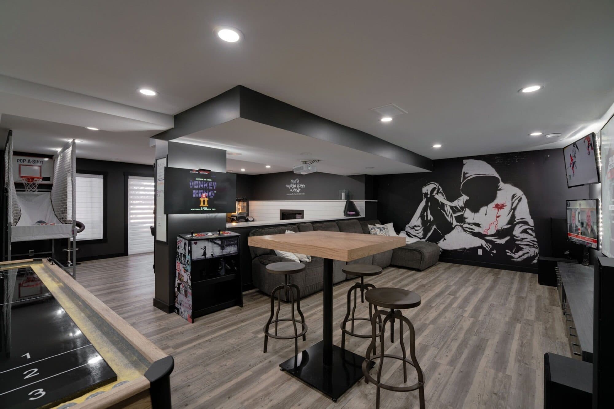 Basement rec room with shuffleboard, bar stools and basketball hoop
