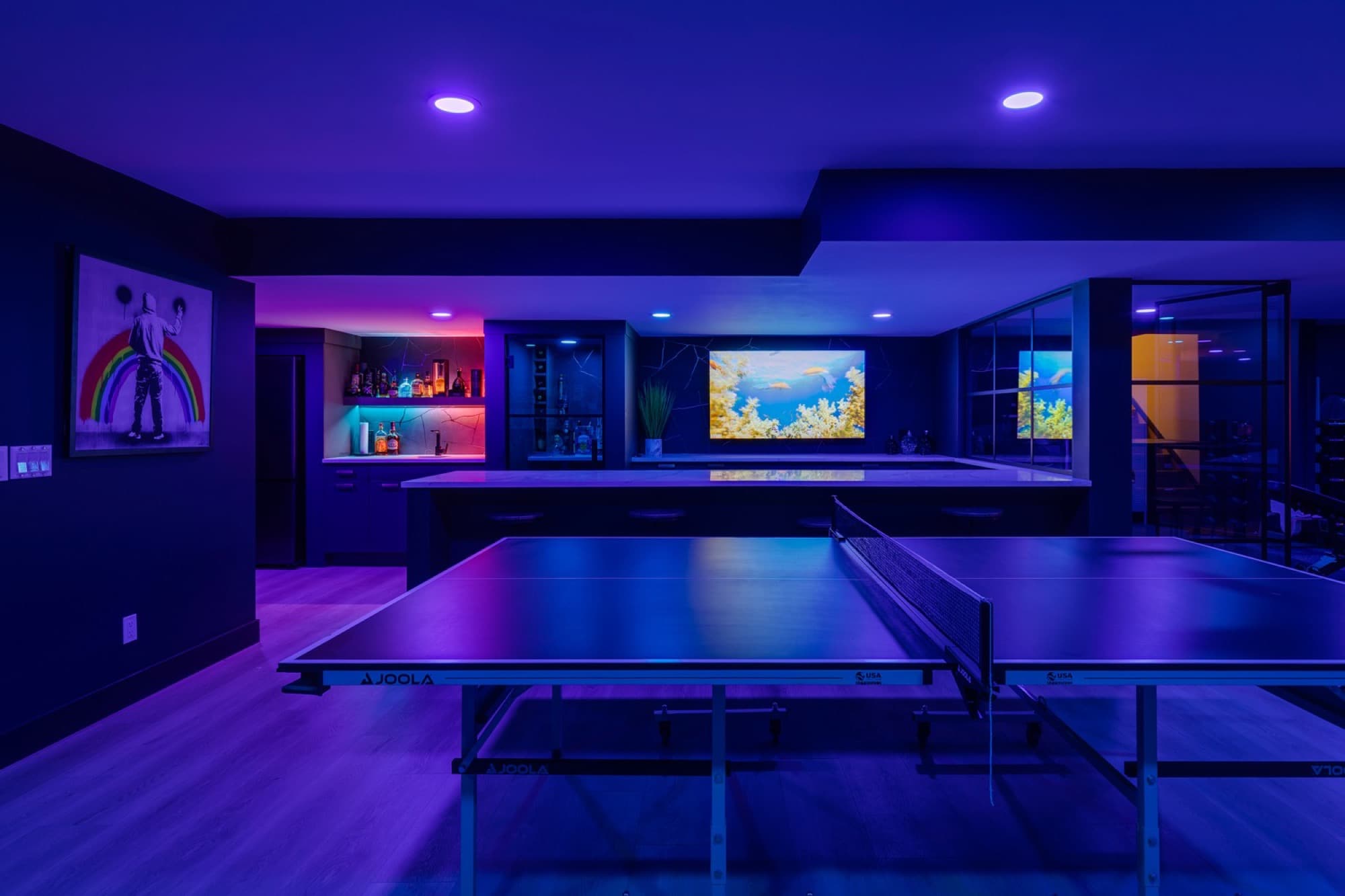 Neon-lit basement games room with ping pong table and bar
