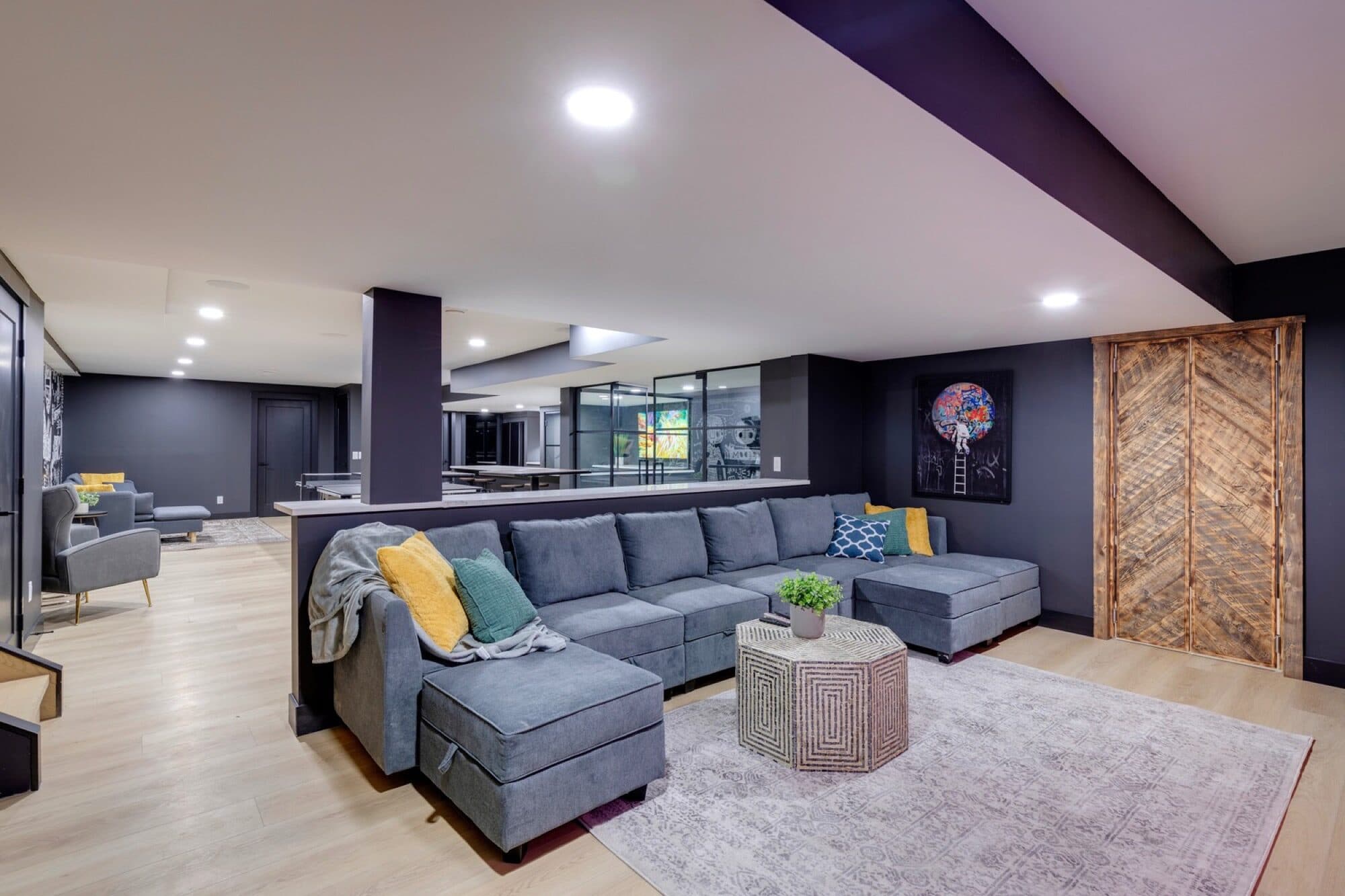 Basement lounge with grey sectional, reclaimed barn door and graffiti art