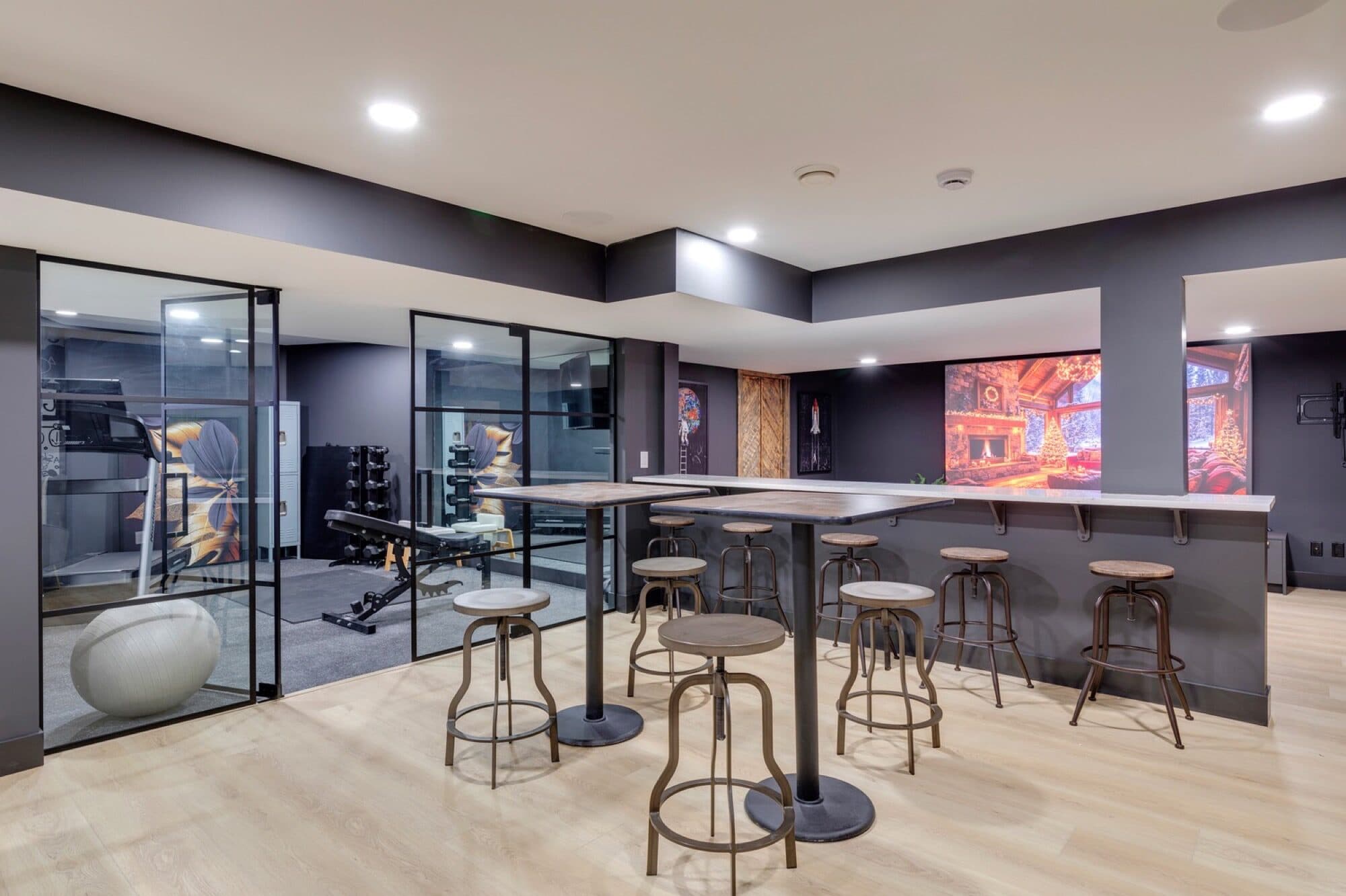 Basement gym behind a glass wall with high-top bar seating