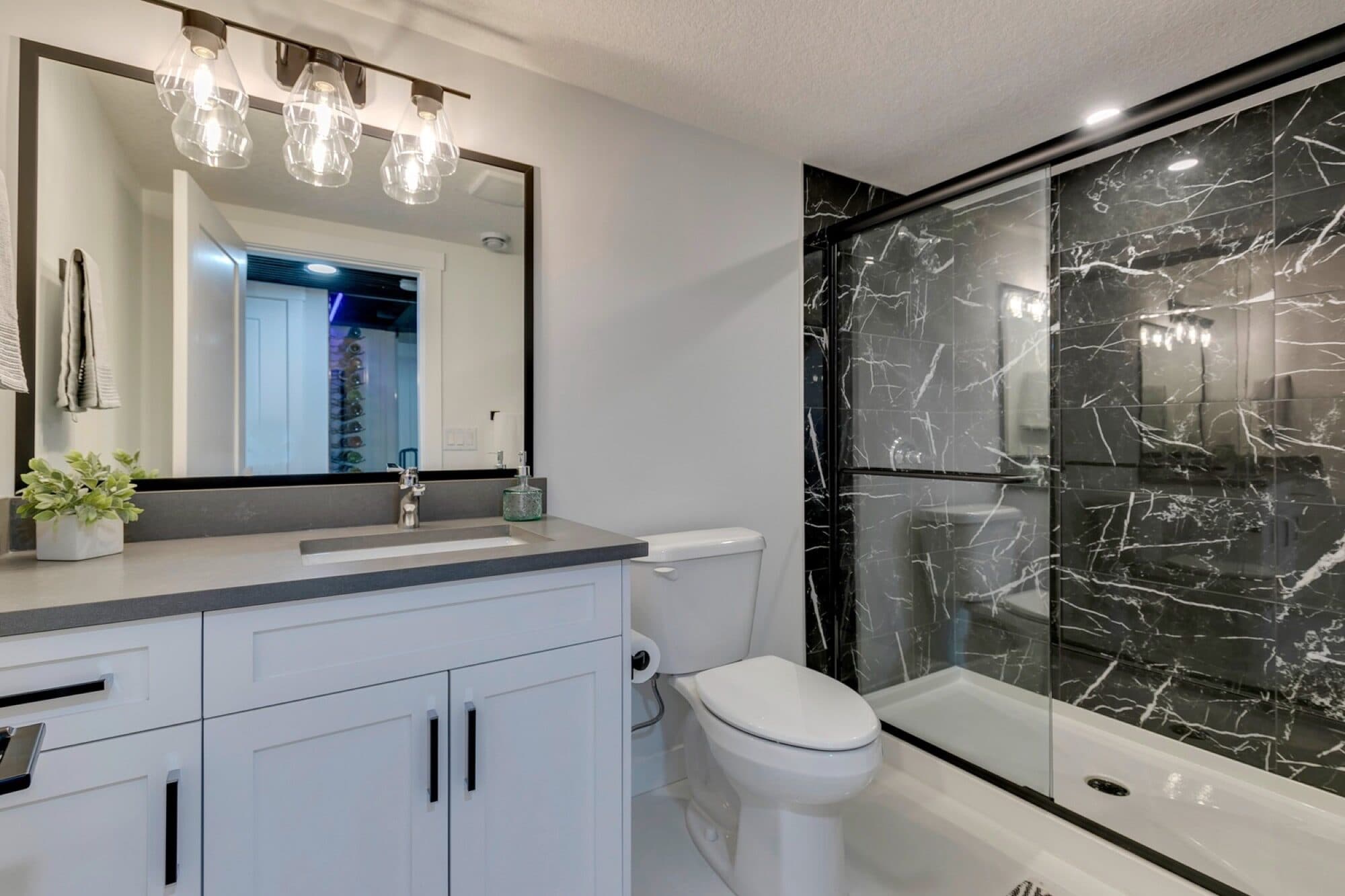 Basement bathroom with black marble shower and white vanity