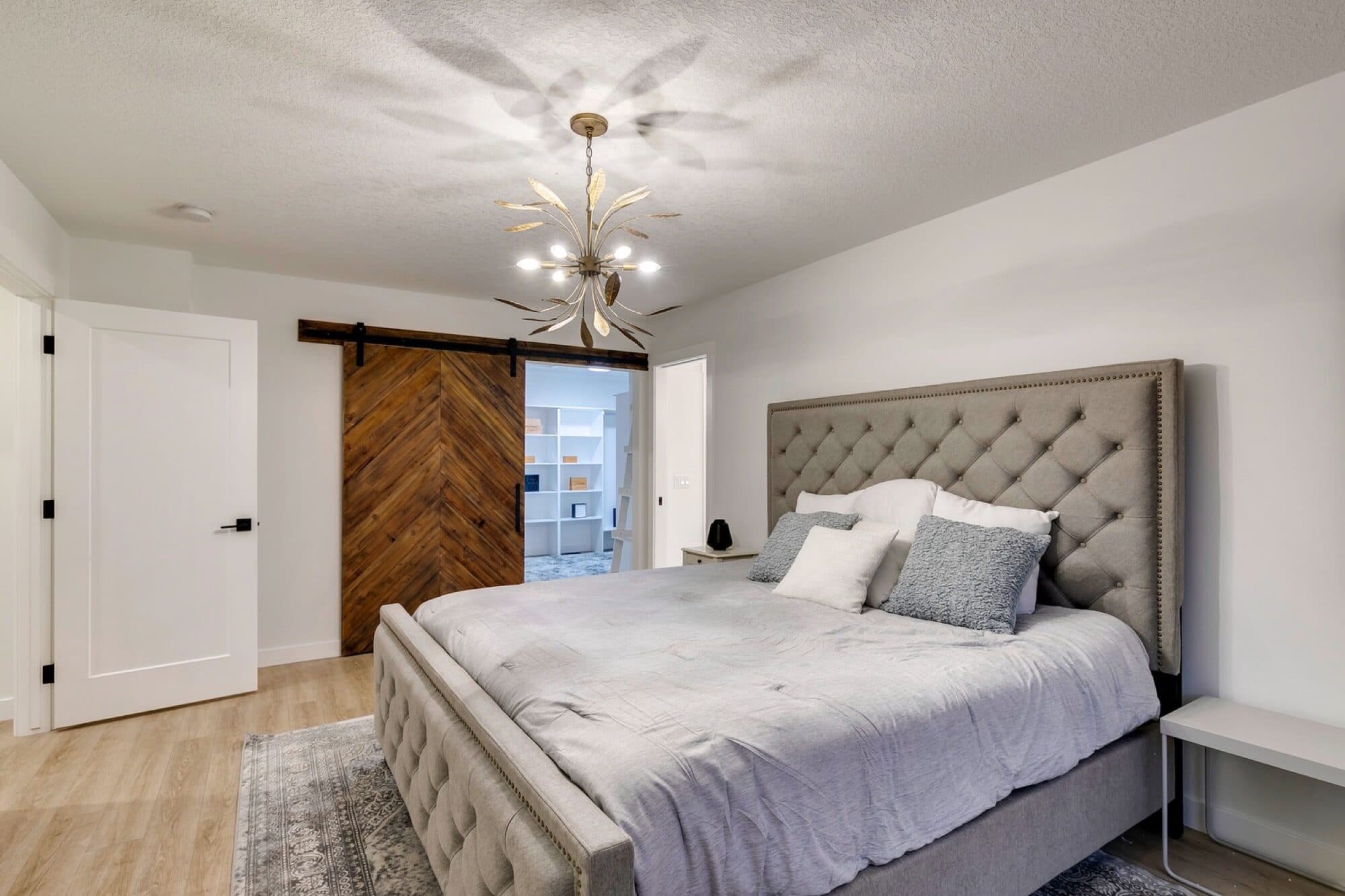 Basement bedroom with herringbone barn door and tufted headboard