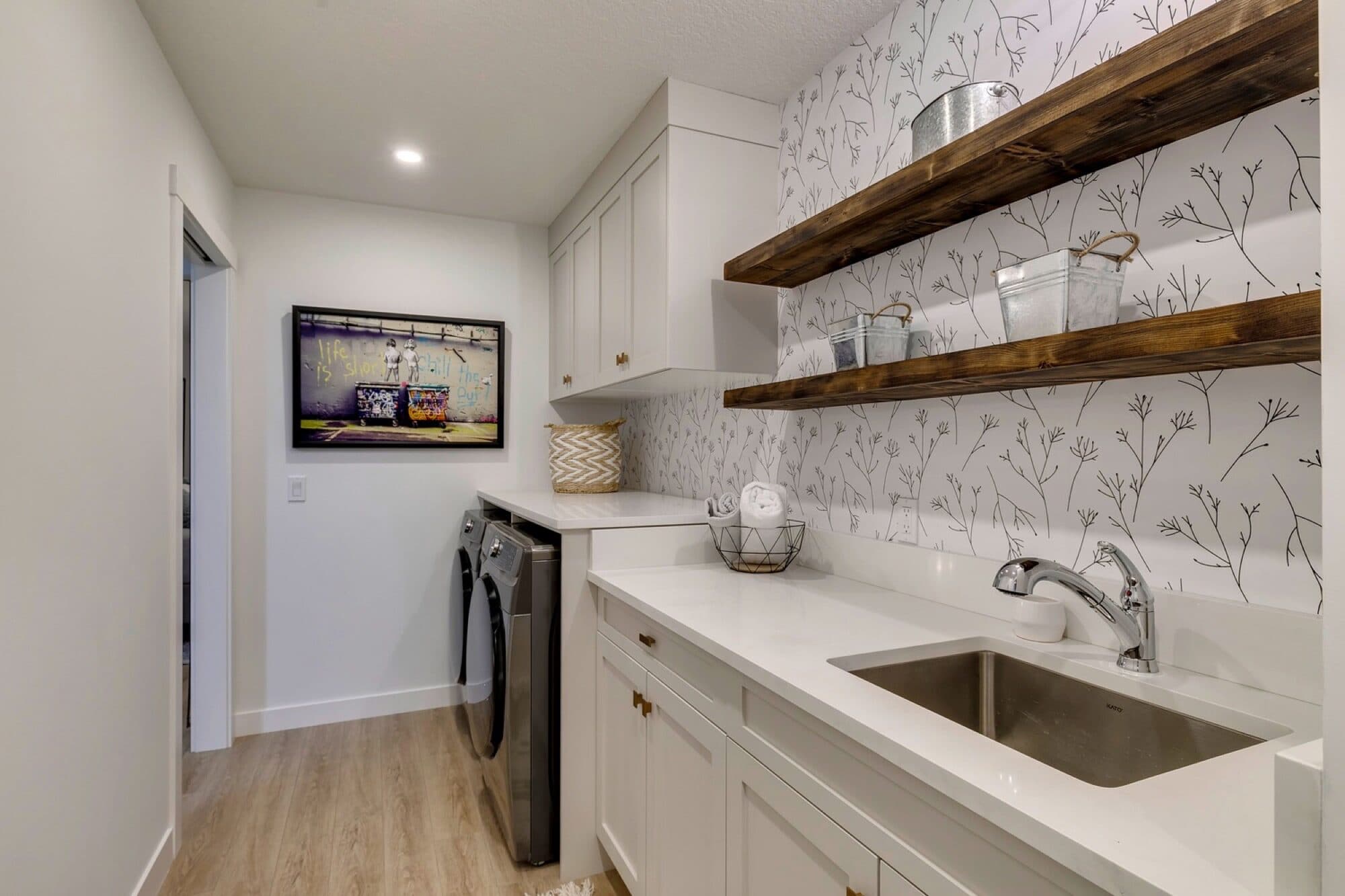 Finished laundry room with wallpaper backsplash and wood shelves