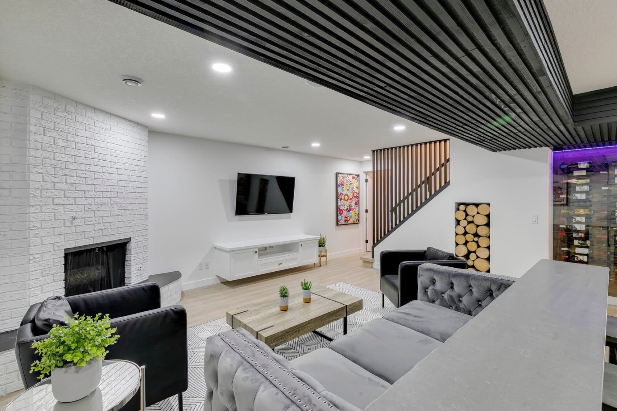 Basement rec room with white brick fireplace and slatted ceiling