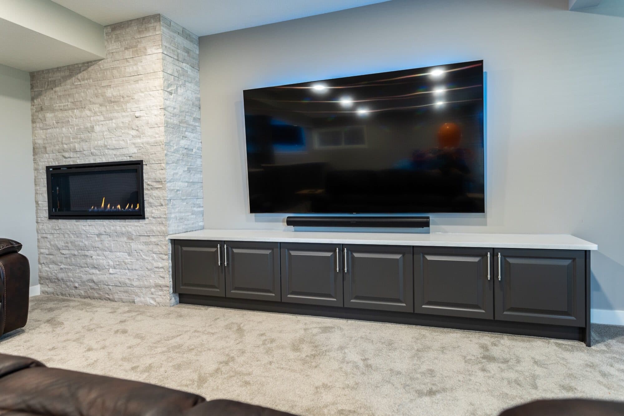 Stone-surround basement fireplace, TV built-in and leather sofa