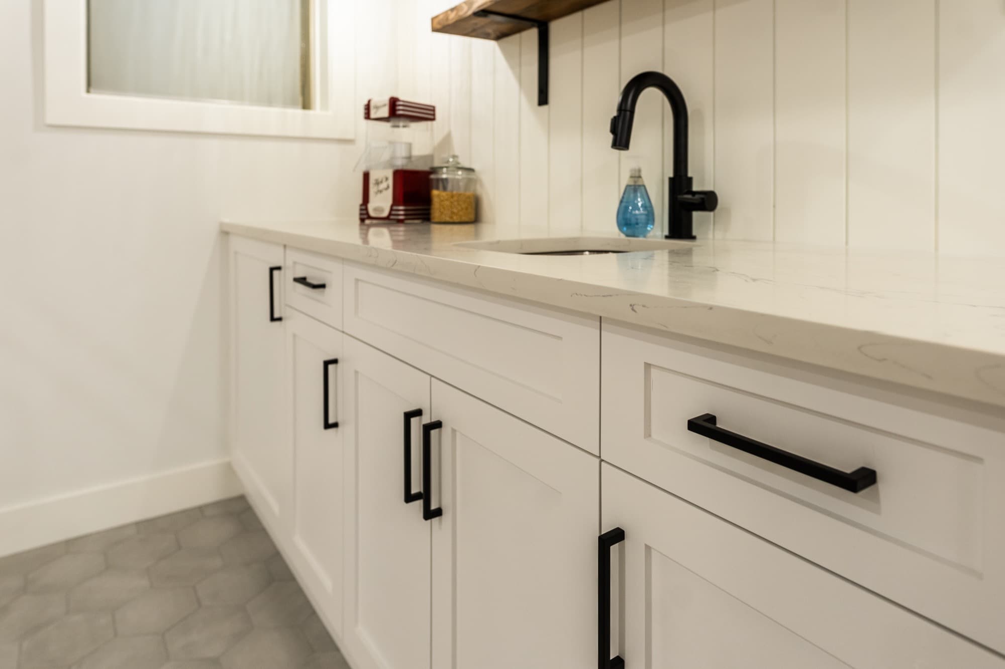 Basement wet bar close-up with quartz counter and black faucet