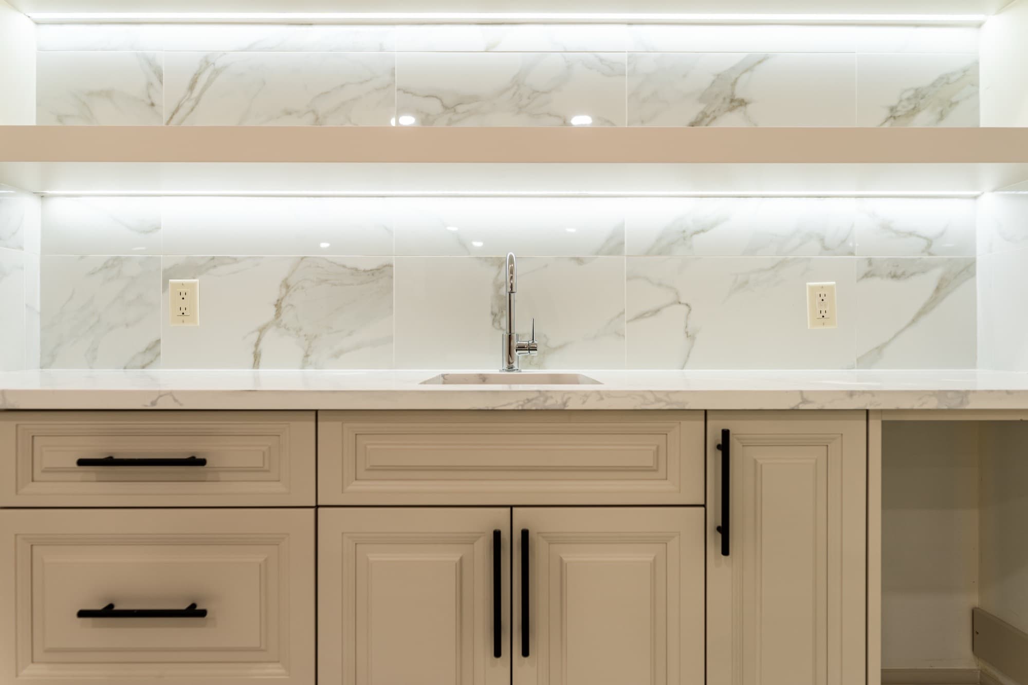 Elegant cream bar cabinet with marble-look tile and LED shelf lighting