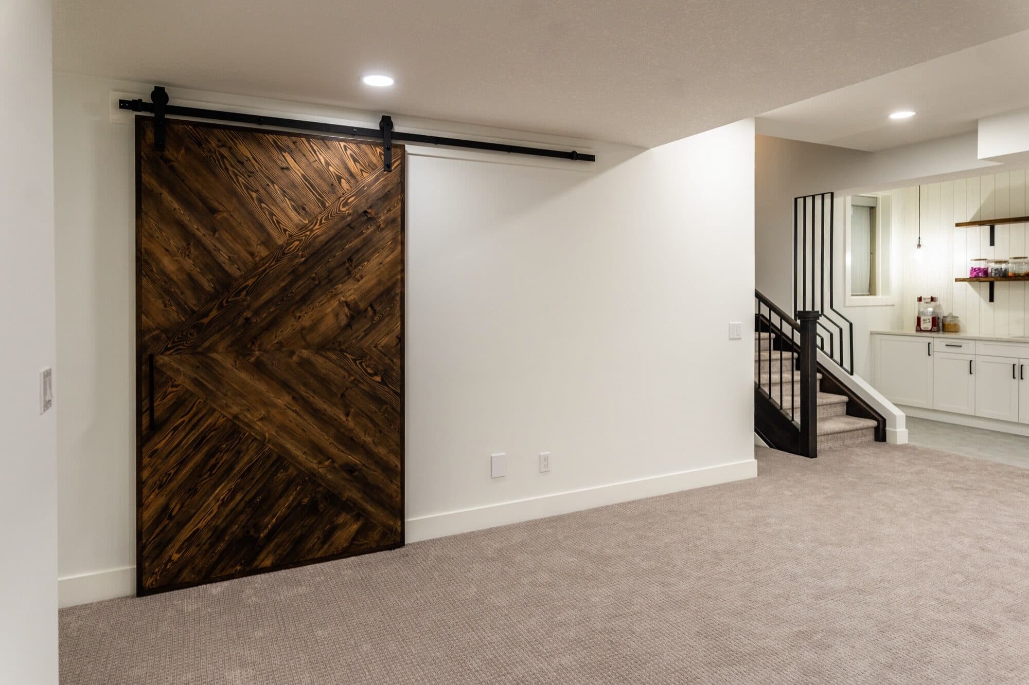 Custom herringbone barn door with basement bar visible behind
