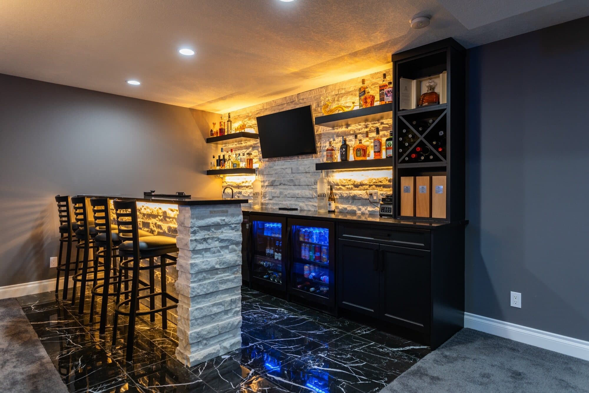 Premium bar with lit stone backsplash, bar stools and wine rack