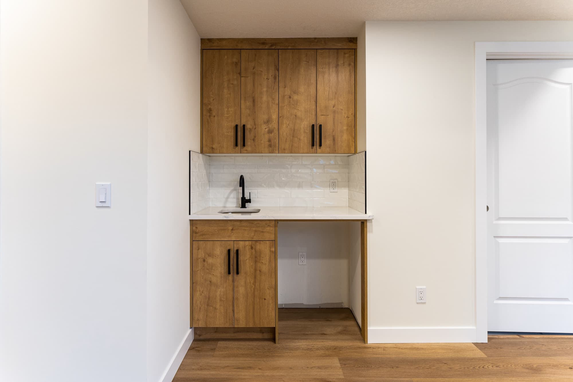 Natural wood kitchenette with quartz counter and subway tile backsplash