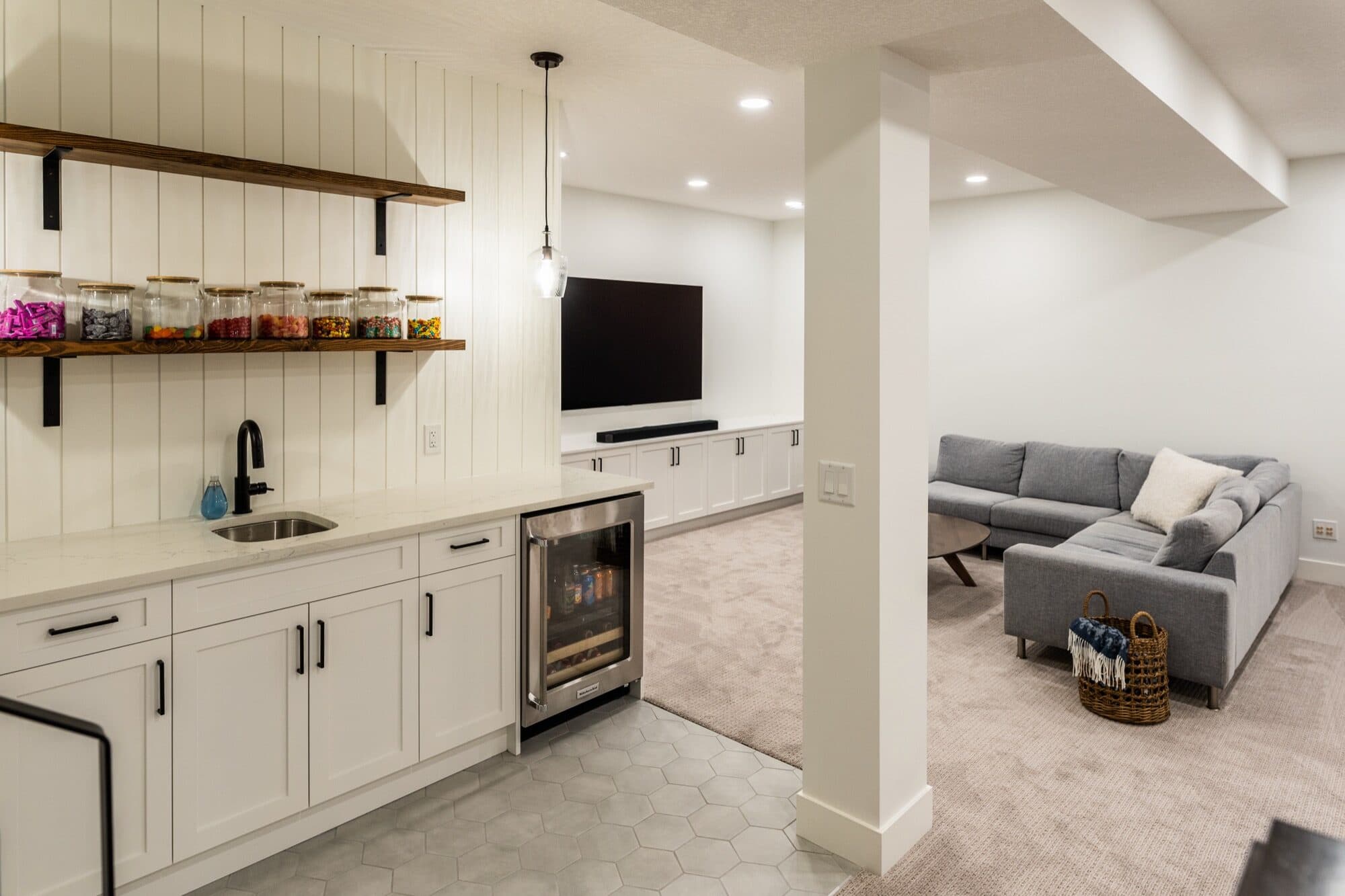Open-plan basement bar and rec room with wine fridge and sectional