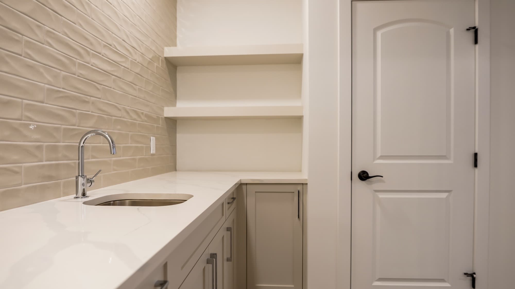 Basement bar area with textured tile backsplash and floating shelves
