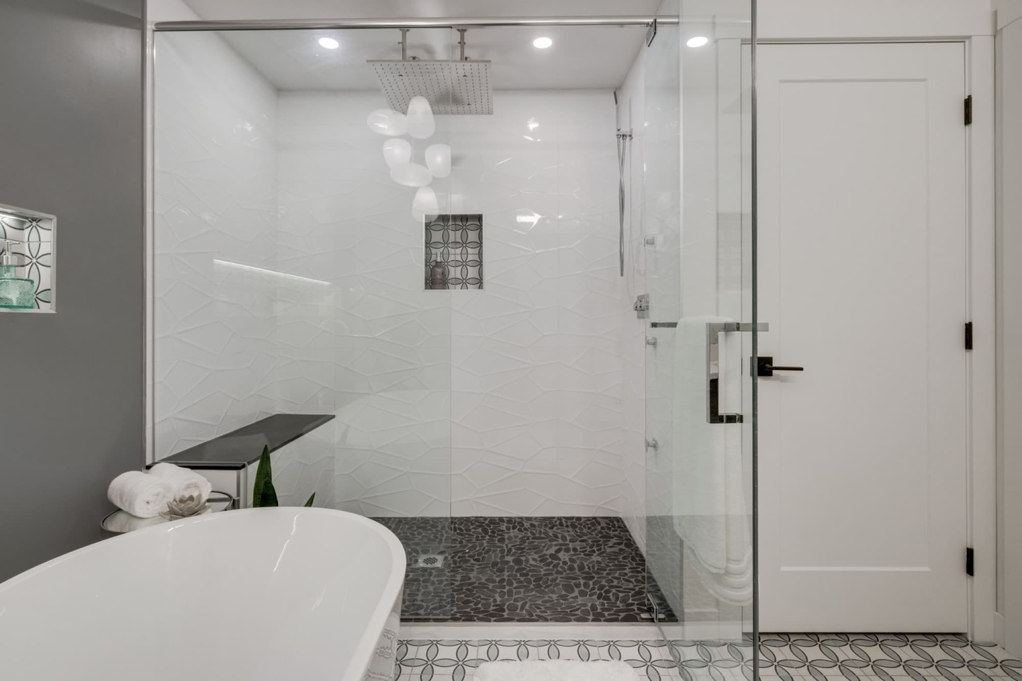 Ensuite shower with pebble floor and soaker tub in grey bathroom