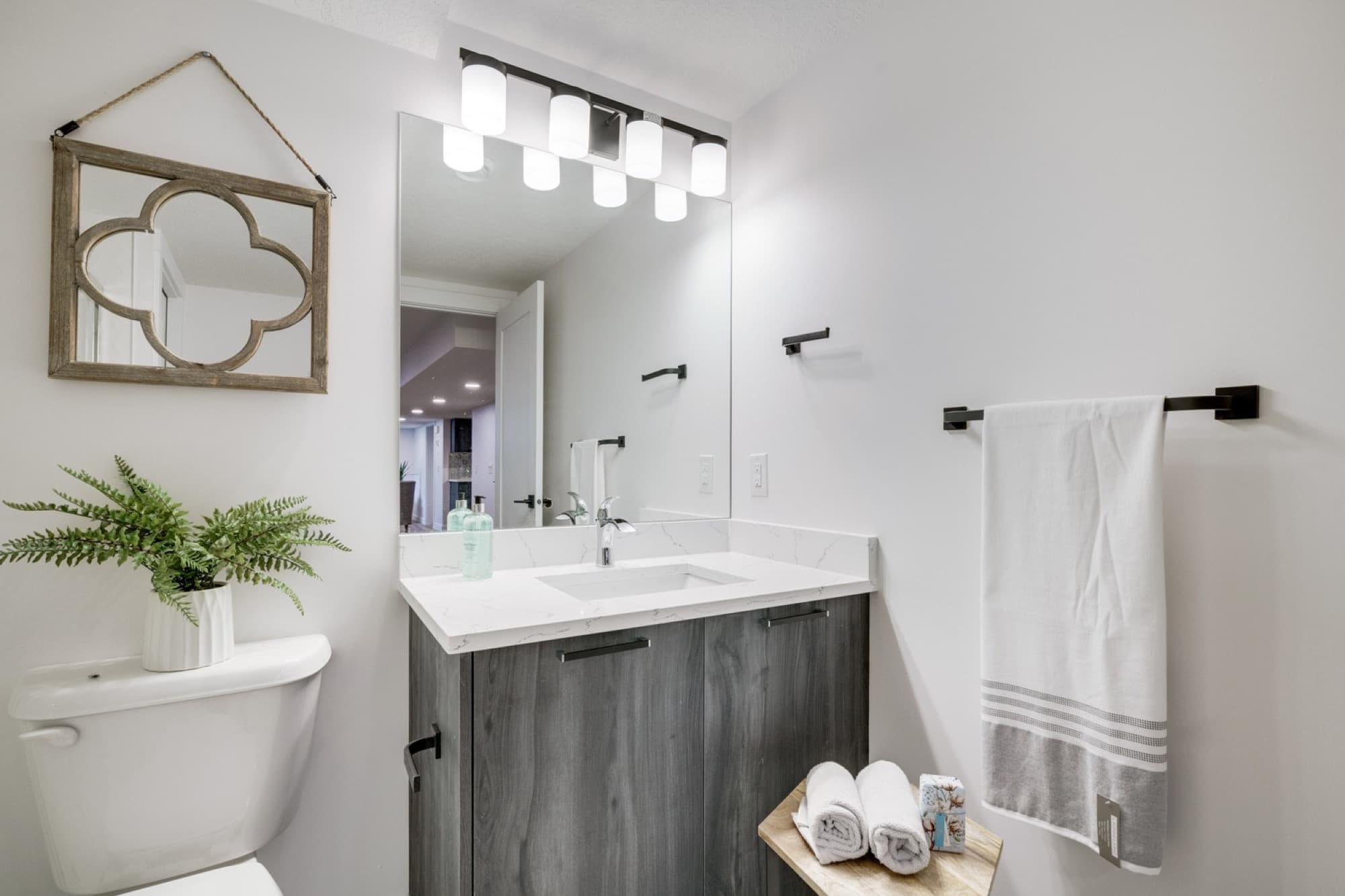 Basement bathroom vanity with dark wood cabinet and quartz countertop