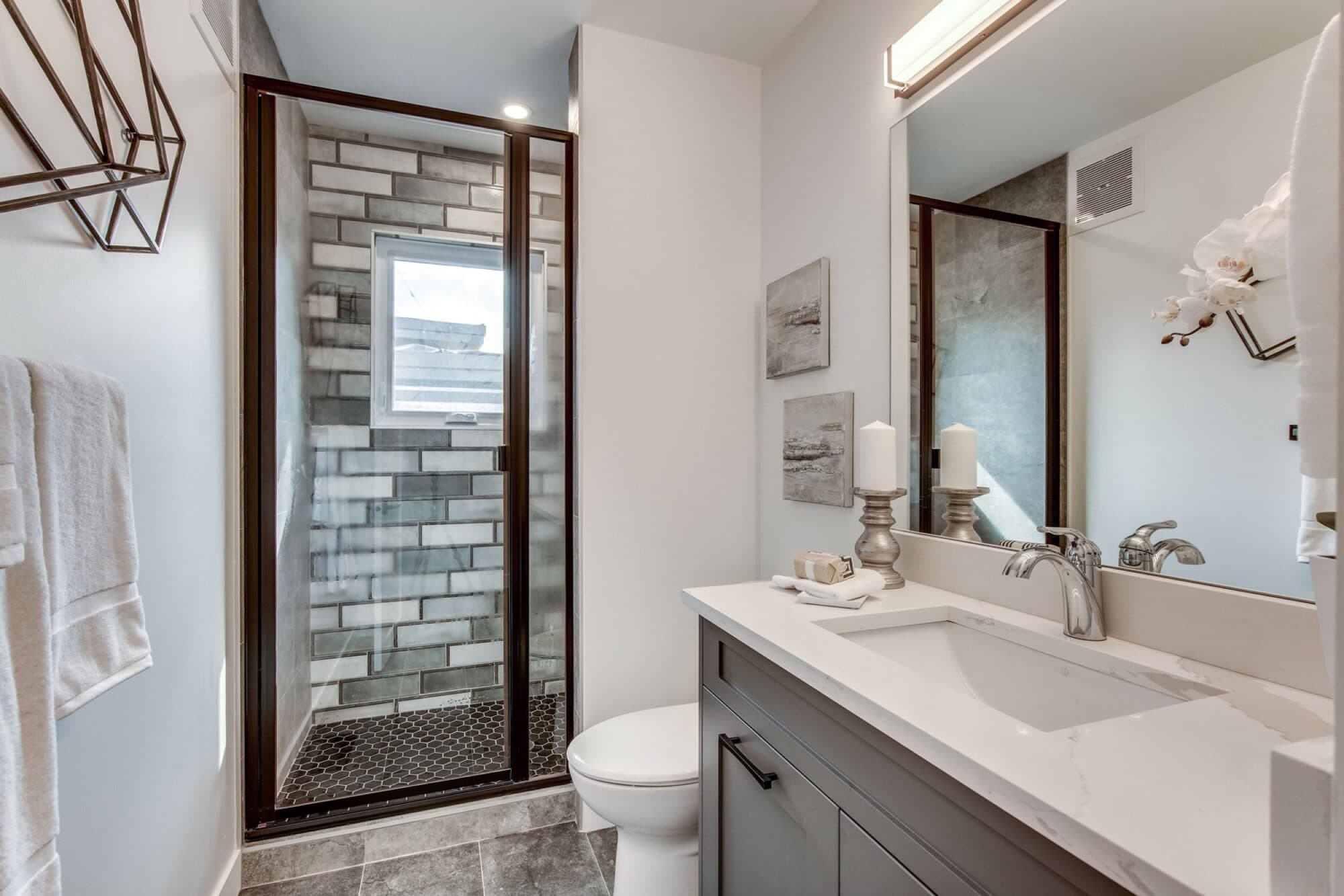 Basement bathroom with brick tile shower and grey vanity