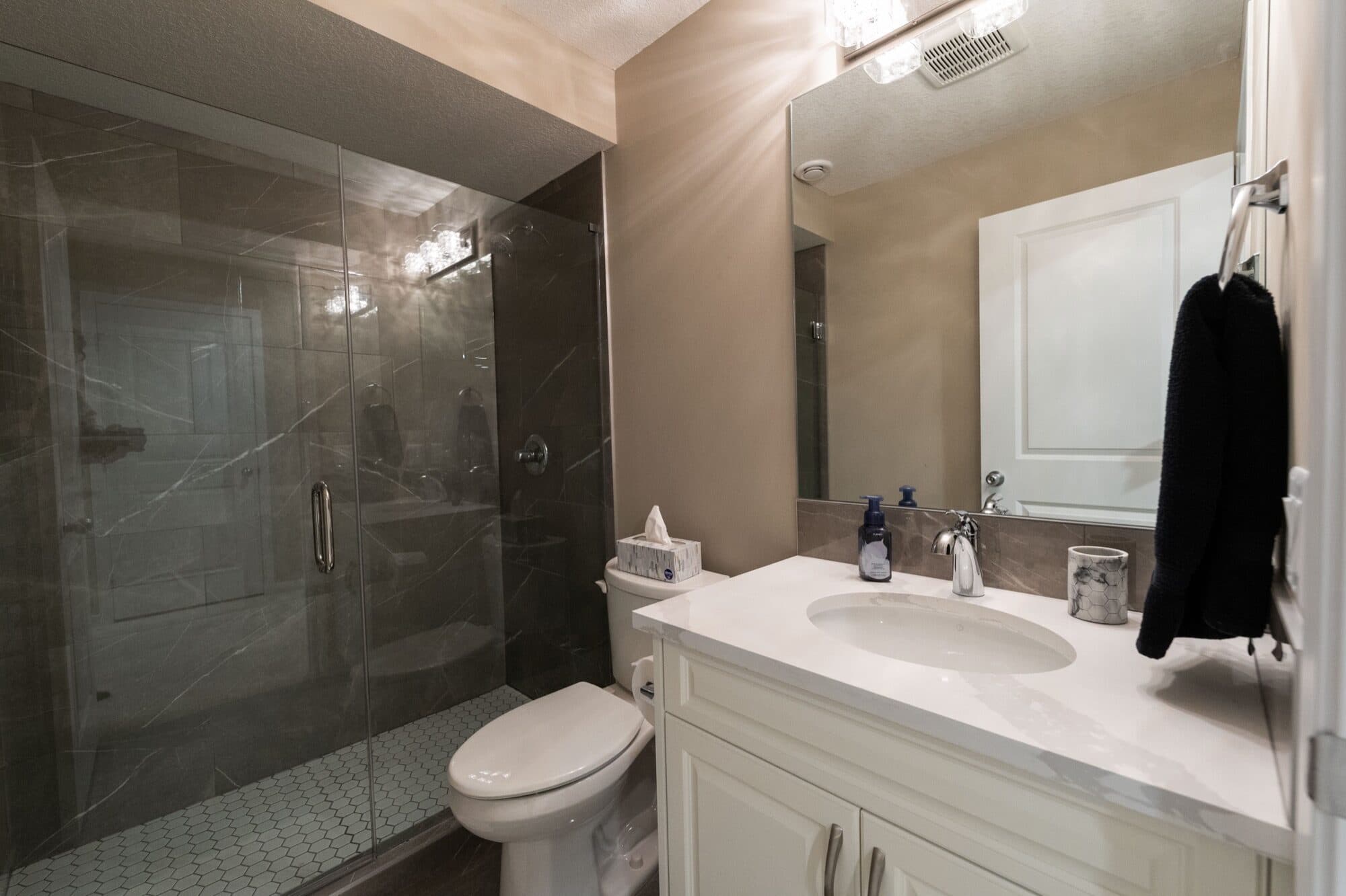 Dark tile basement bathroom with glass shower and white vanity