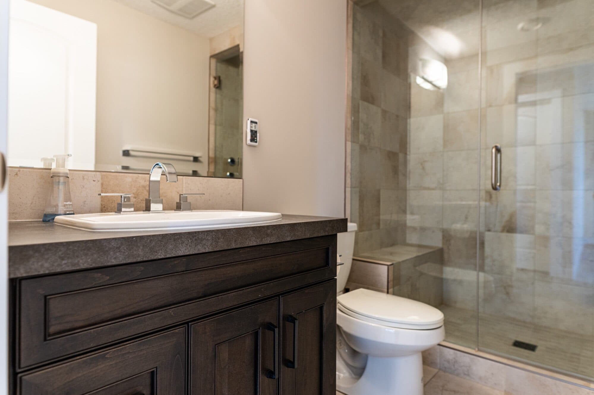 Basement bathroom with dark vanity, black marble tile and glass shower