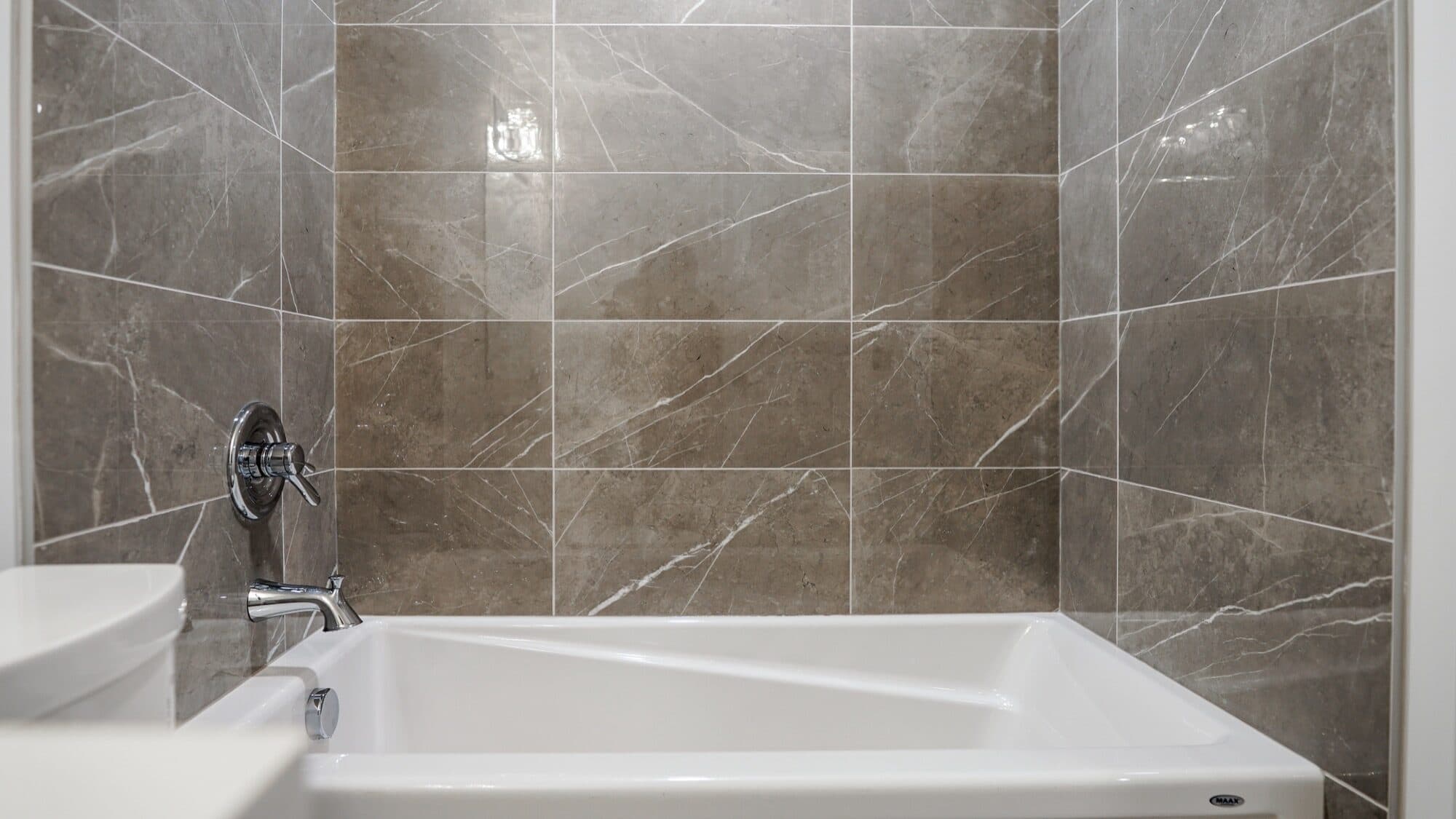 Bright basement bathroom with grey marble tub-surround and white vanity