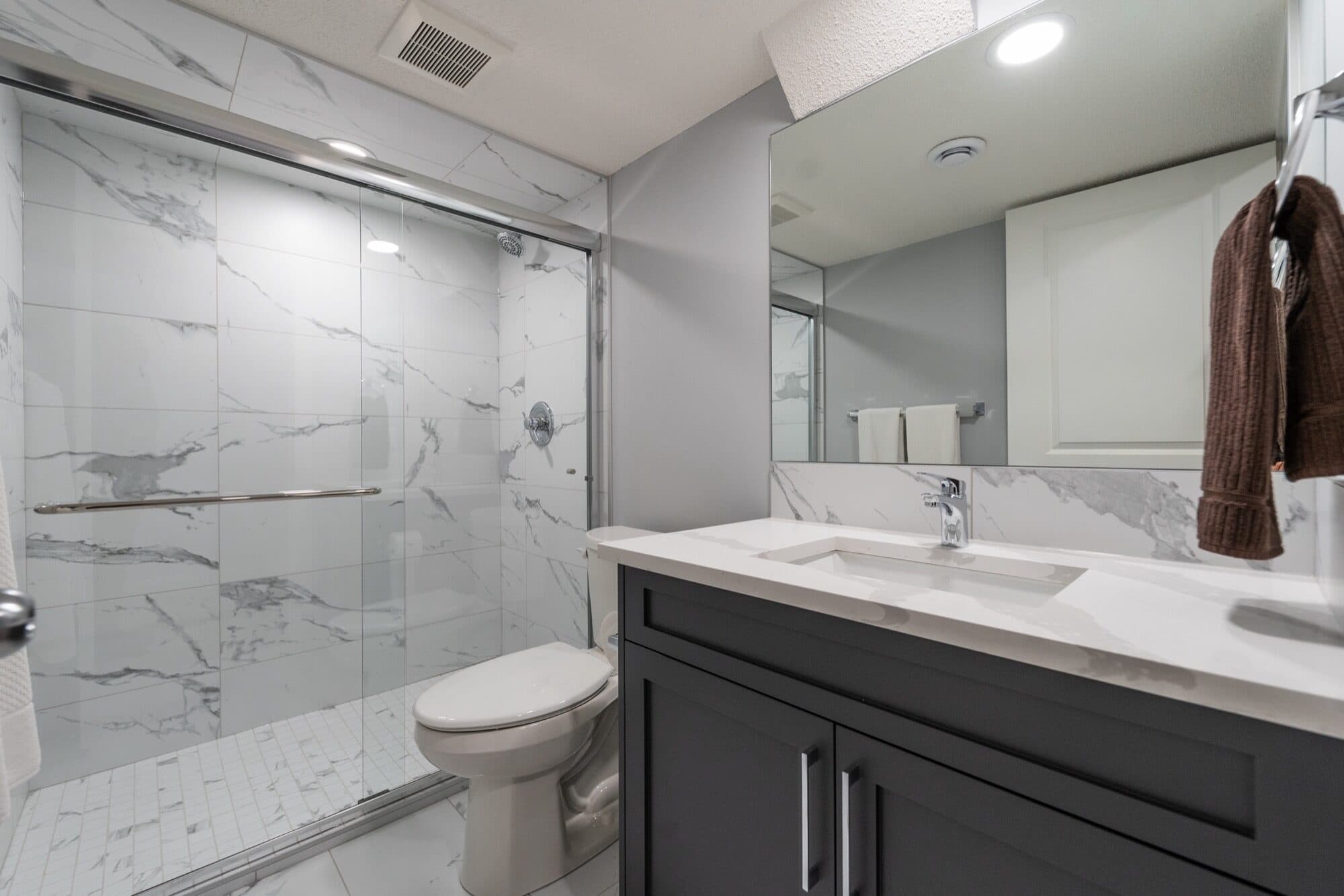 Marble basement bathroom with slider glass shower, alternate angle