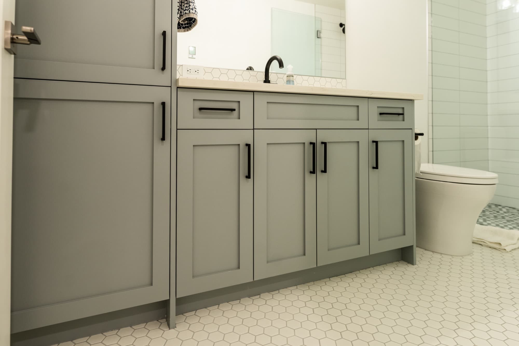Sage green bathroom vanity with hex floor tile and black hardware