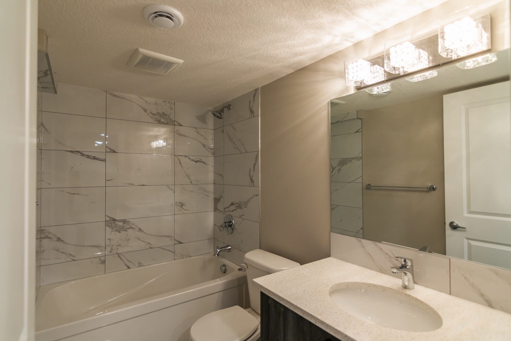 Basement legal suite bathroom with marble tub surround and modern vanity