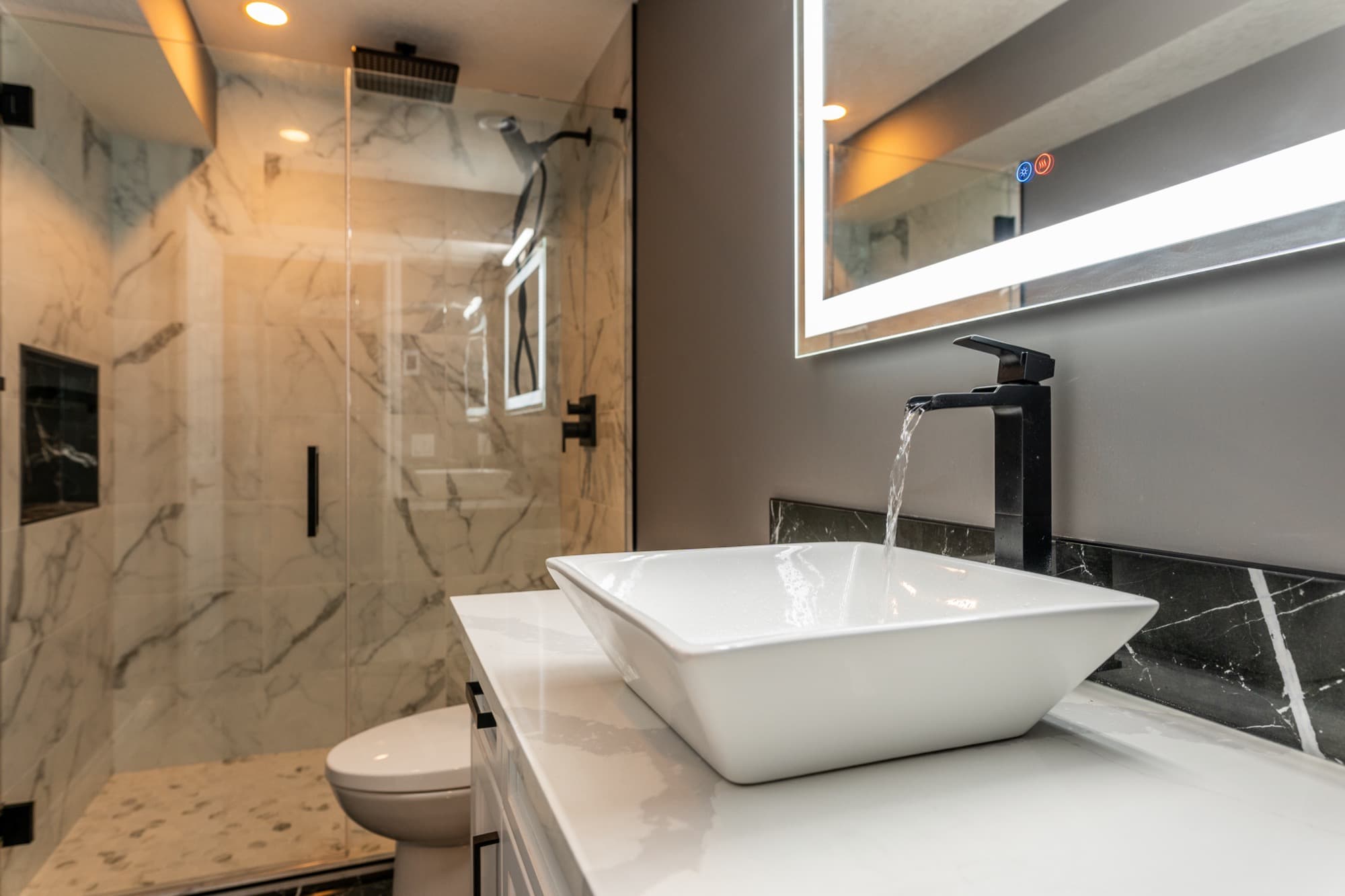 Luxury basement bathroom with vessel sink, marble tile and LED mirror