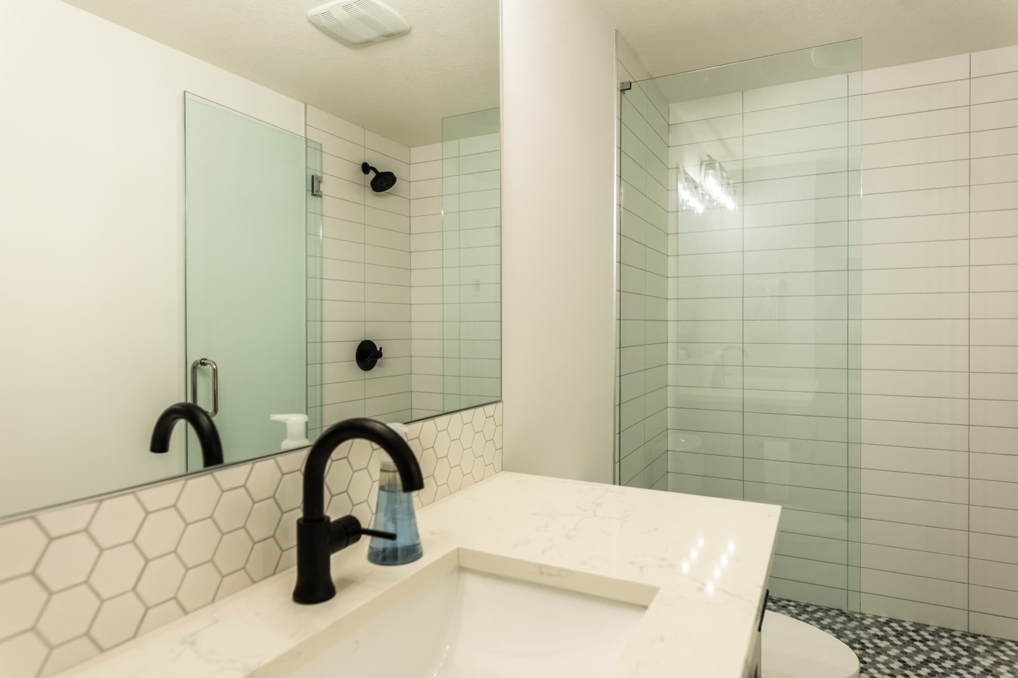 White basement bathroom with hexagon tile backsplash and glass shower