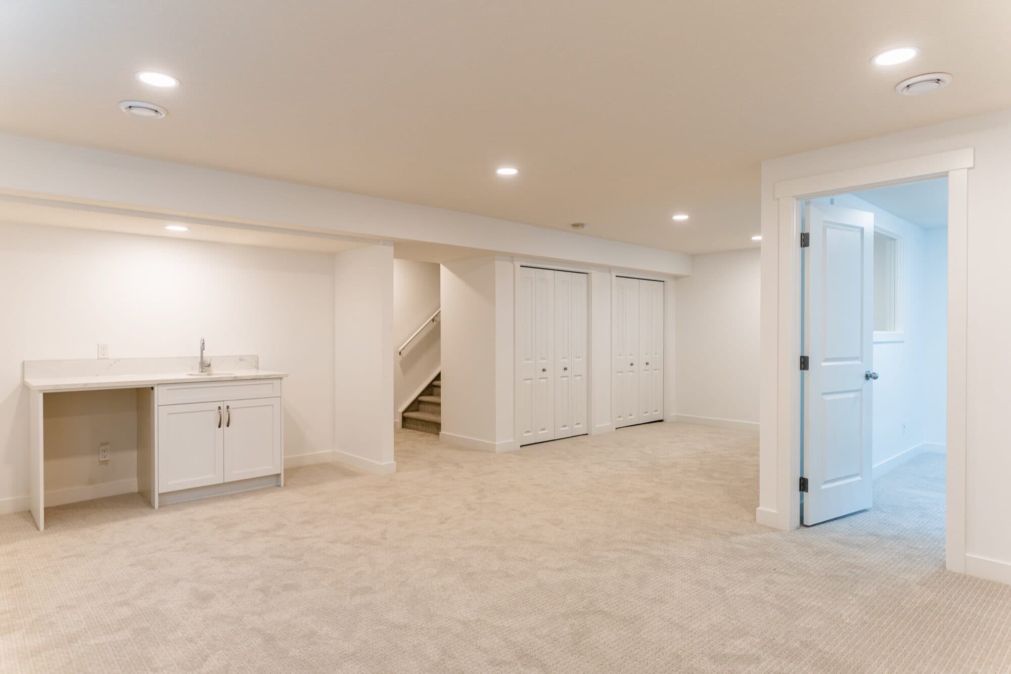 Clean white basement bathroom with marble tile shower and closet