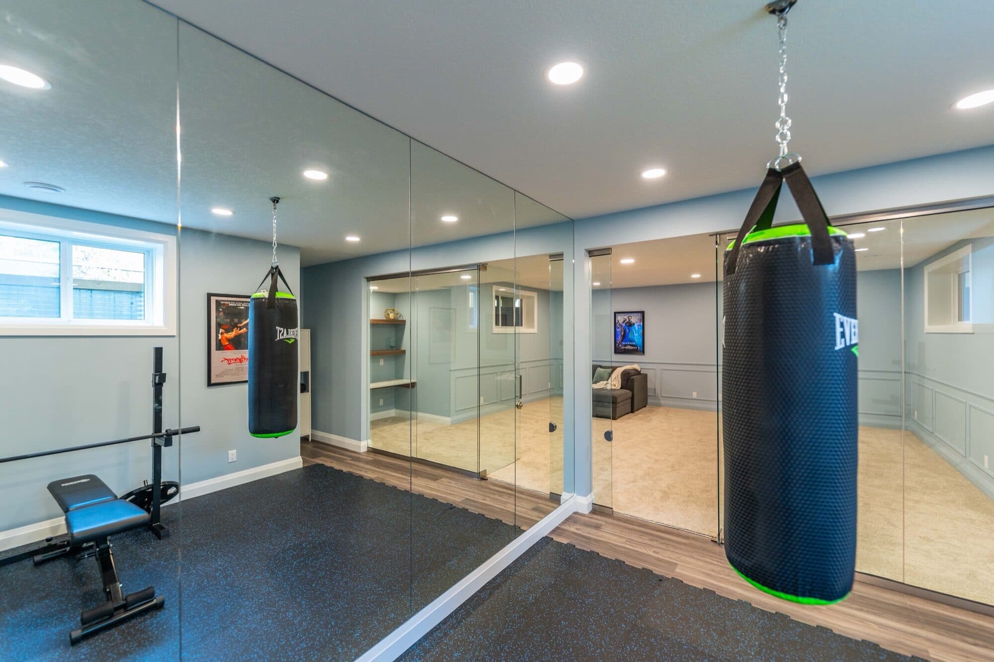 Basement gym with boxing bag, bench and mirror wall