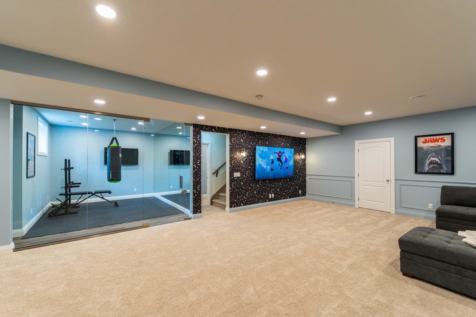 Basement rec room and gym with glass wall, boxing bag and movie posters