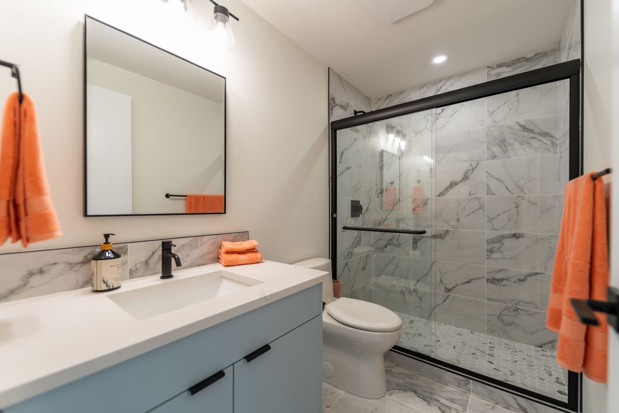 Basement bathroom with blue vanity and marble tile shower