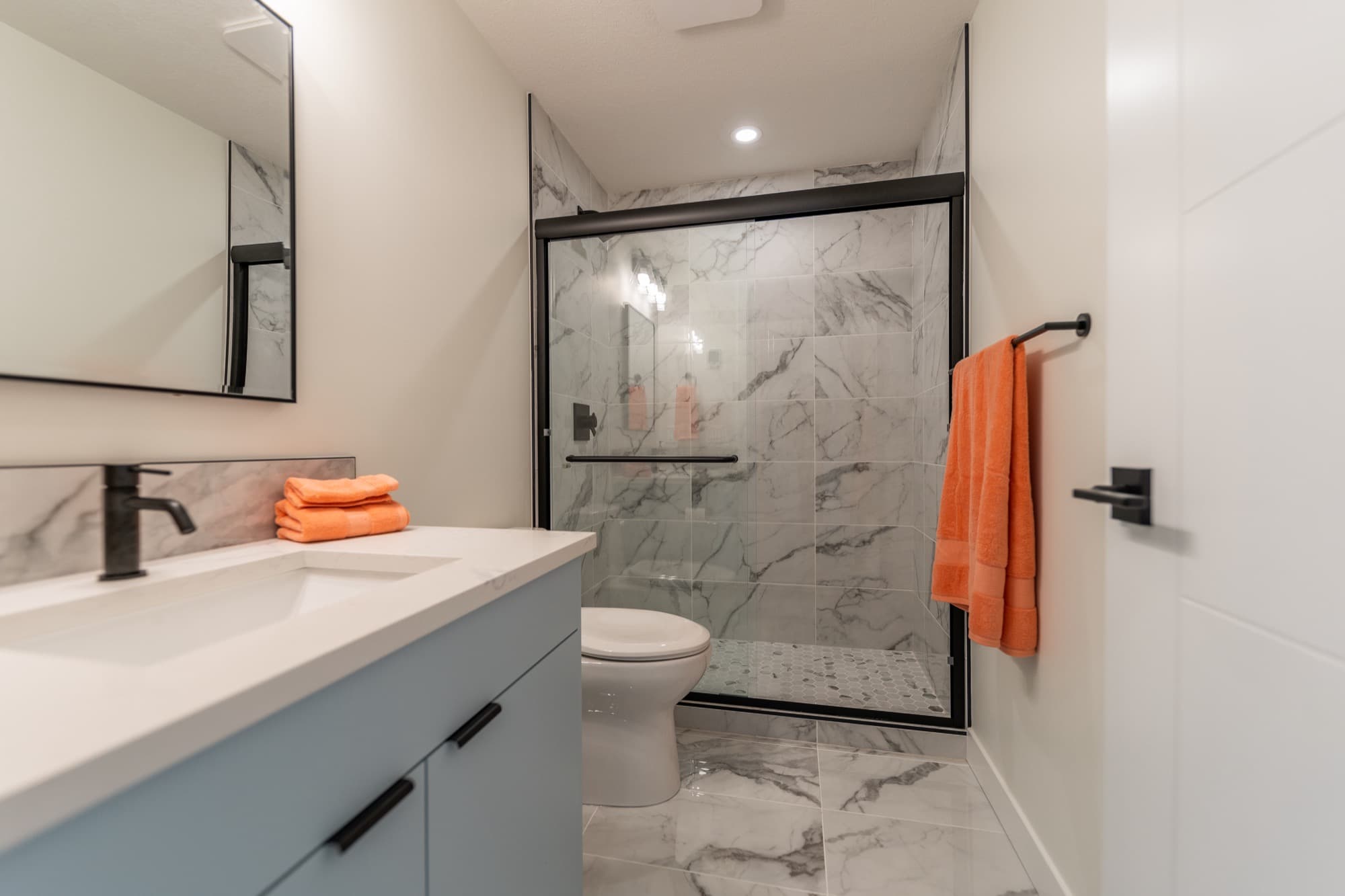 Basement bathroom wide view with blue vanity and marble walk-in shower