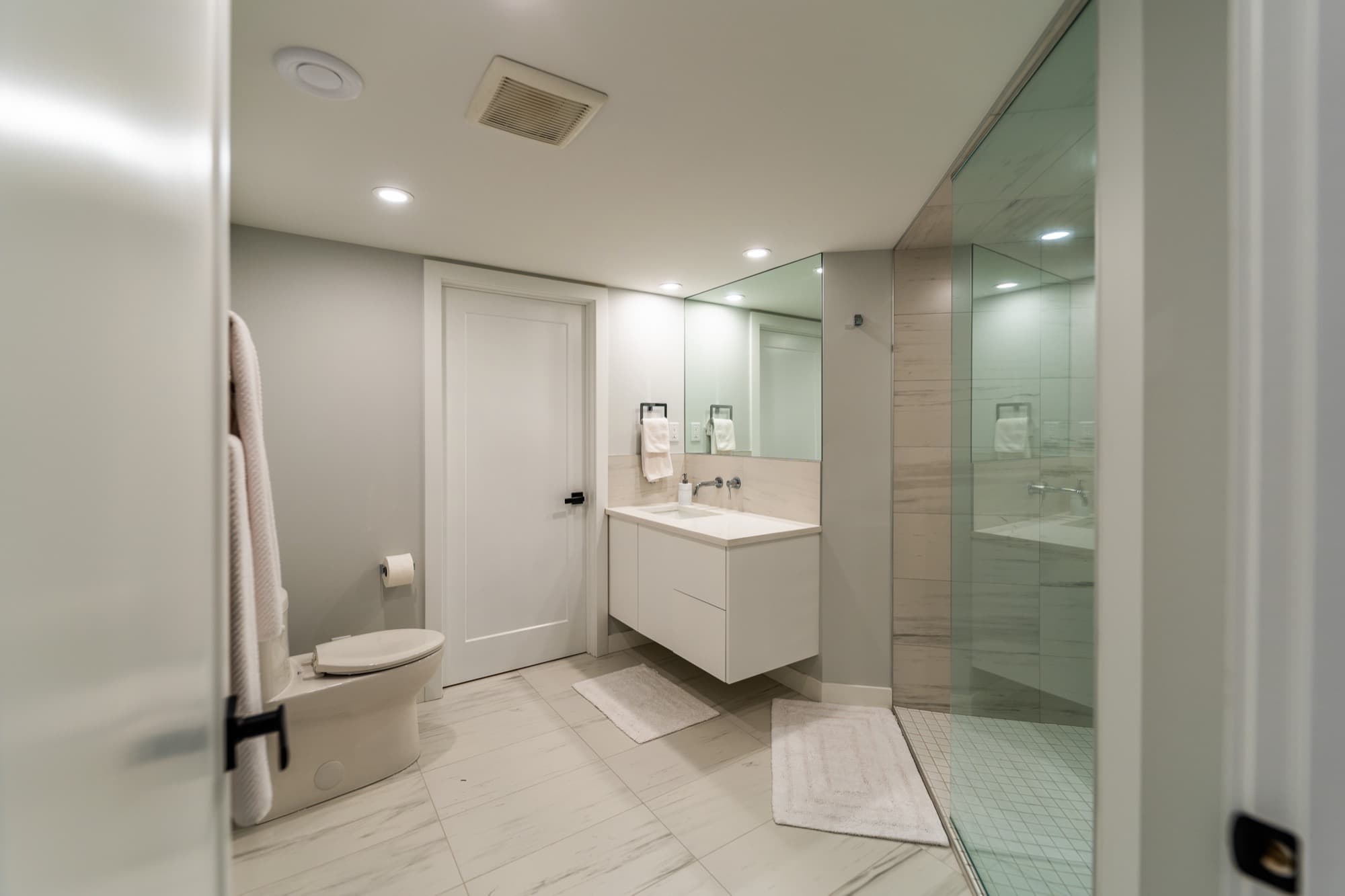 Basement bathroom with floating white vanity and large glass walk-in shower