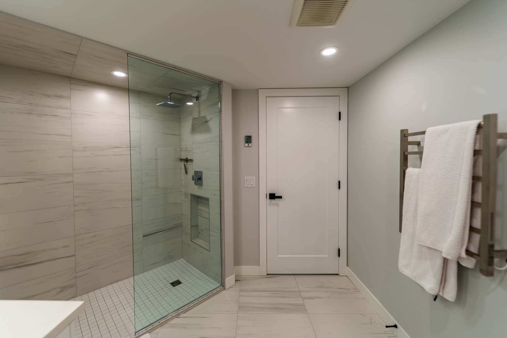 Basement bathroom with glass shower, heated towel bar and wood tile