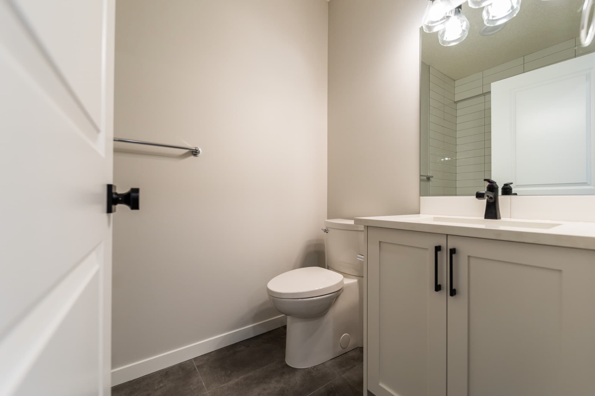 Basement half bath with white shaker vanity and herringbone tile