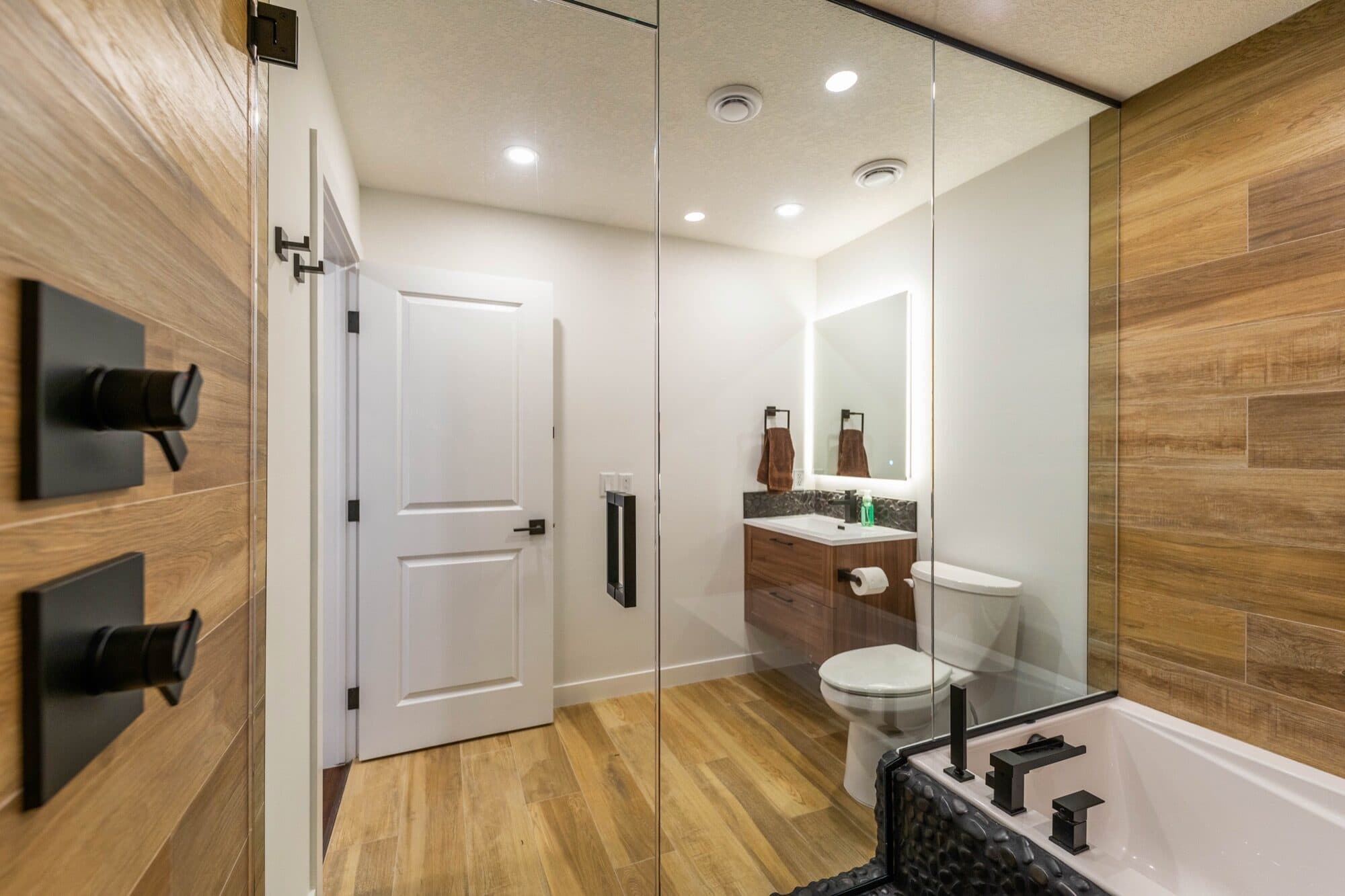 Basement spa bathroom with wood-look tile, soaker tub and pebble shower floor