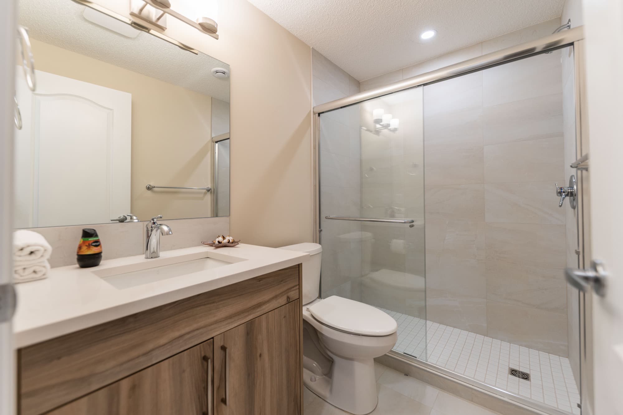 Basement bathroom with wood-grain vanity and glass walk-in shower