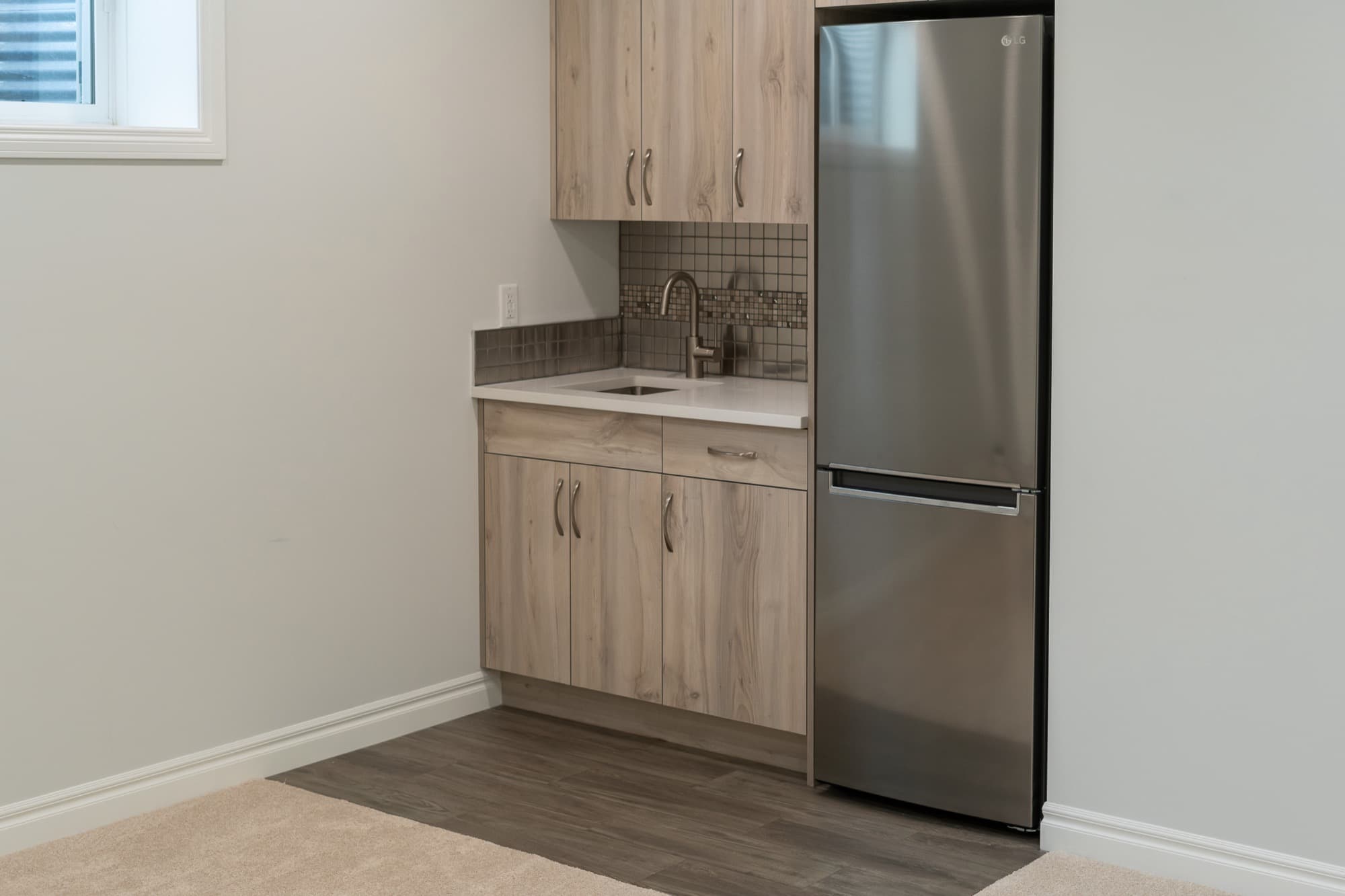 Basement legal suite kitchenette with full fridge and wood cabinets