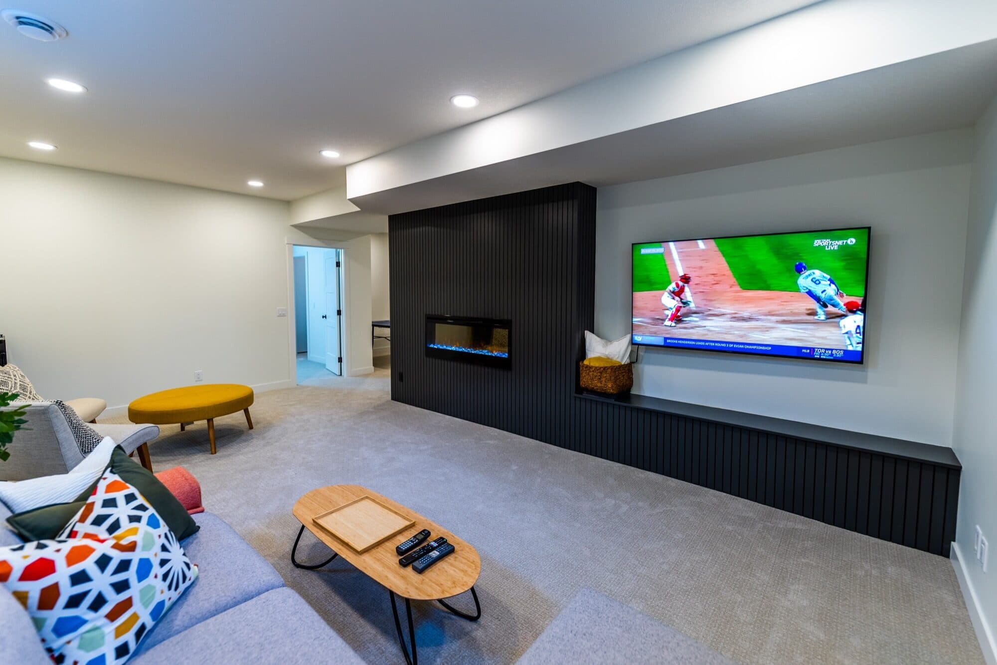 Basement rec room with black slat feature wall, fireplace and large TV