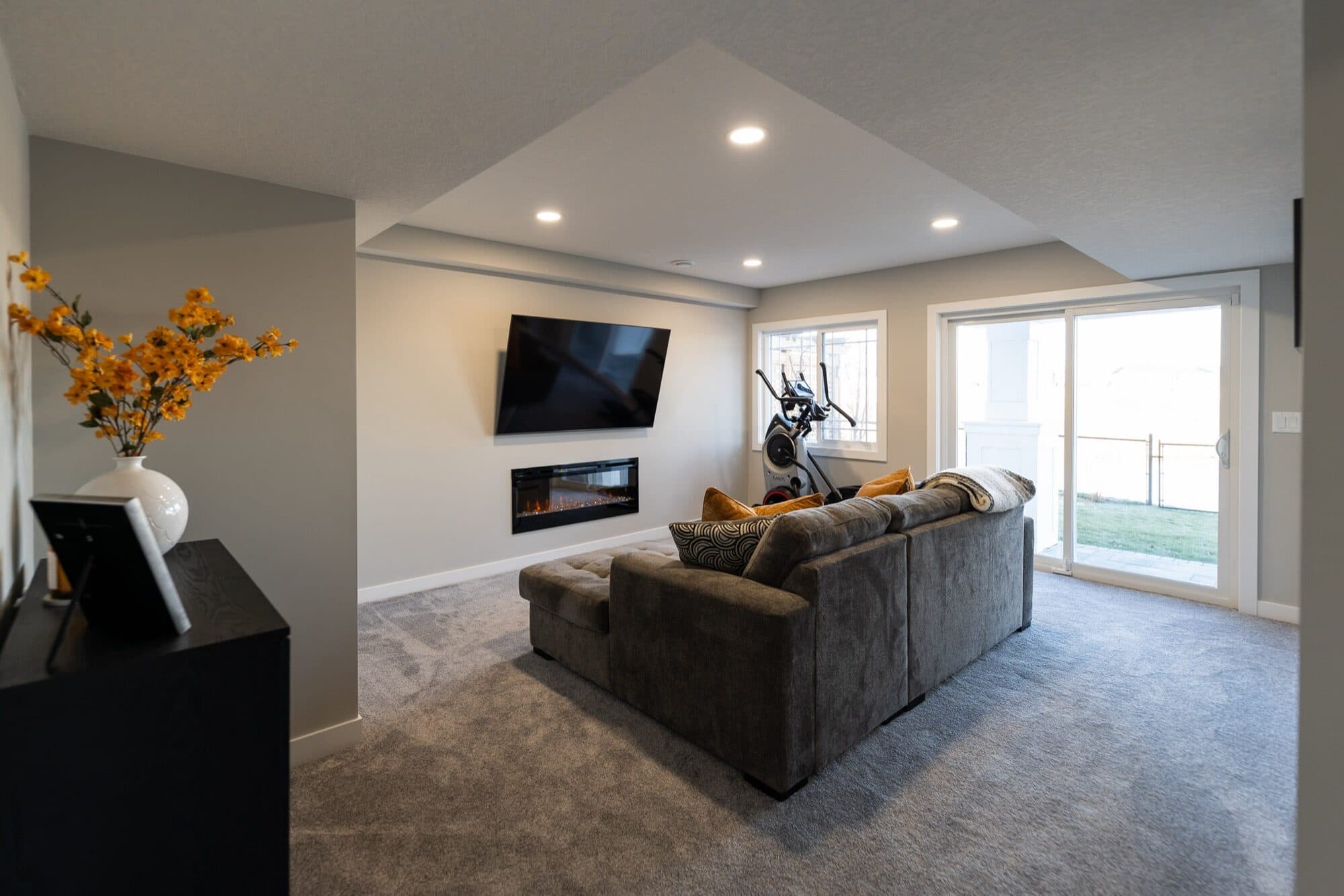 Basement rec room with electric fireplace, sectional sofa and walkout door