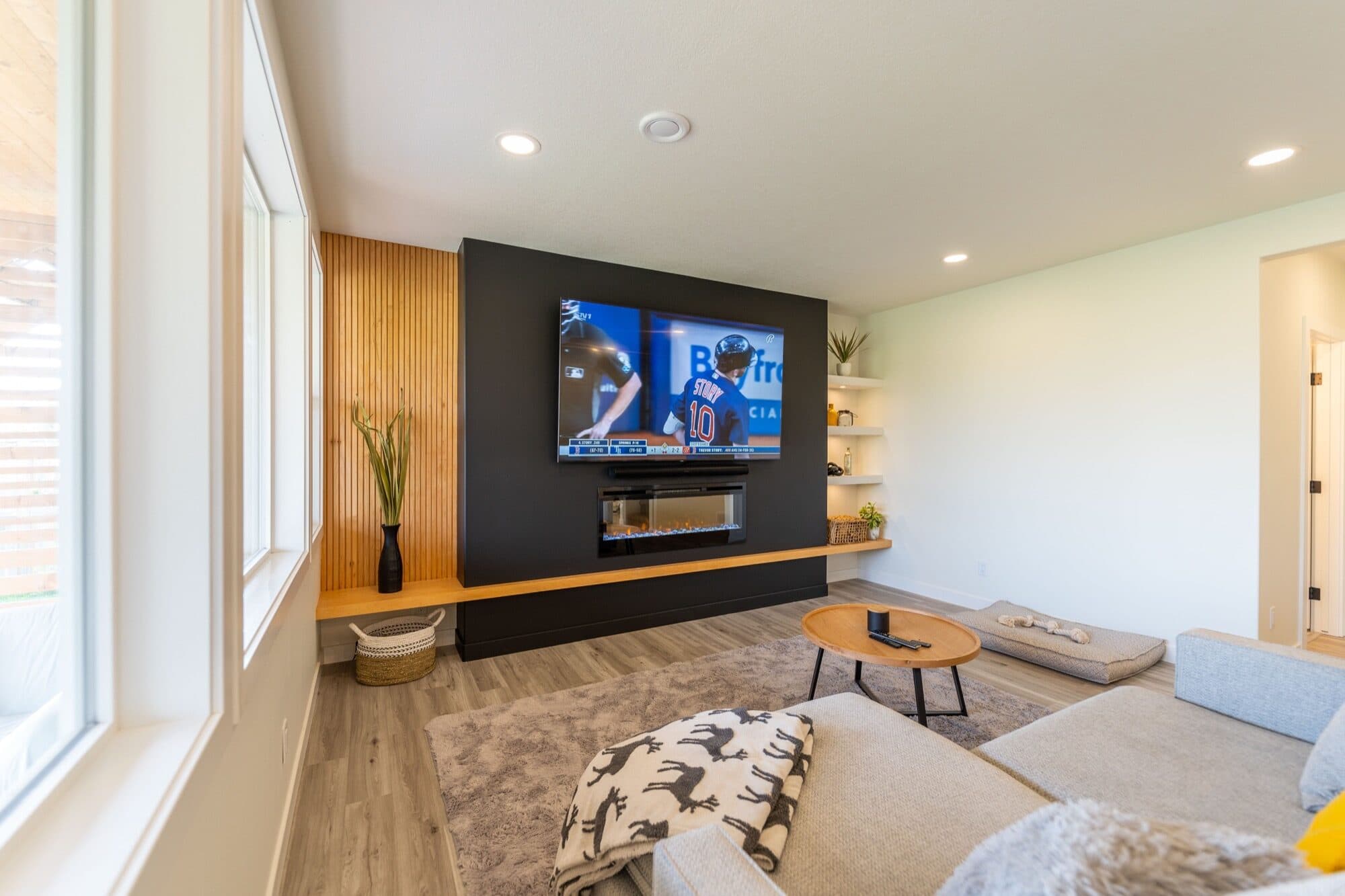 Basement rec room with black fireplace feature wall, wood slat accent and TV
