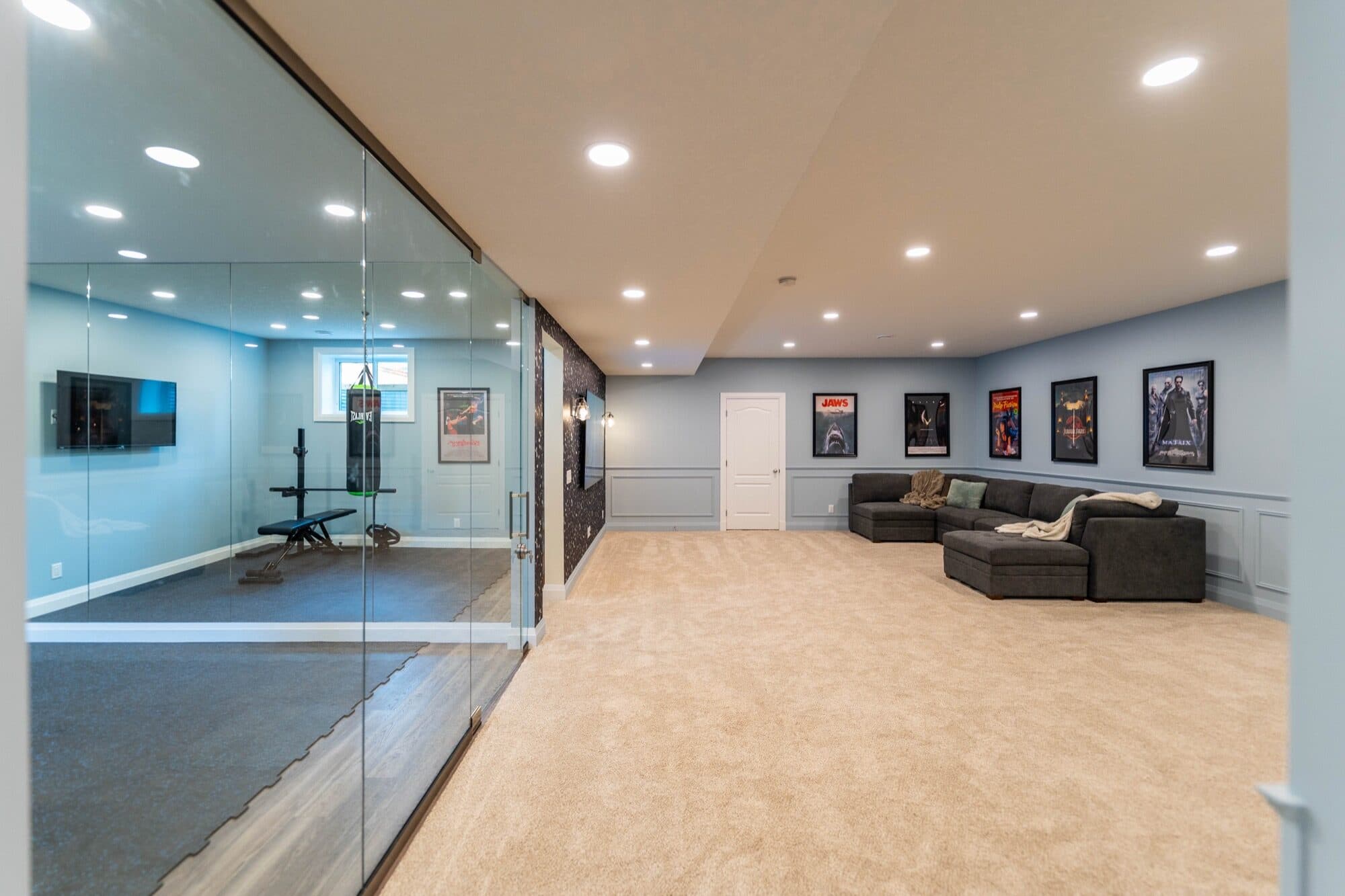 Basement rec room with glass-wall gym, sectional and movie poster gallery