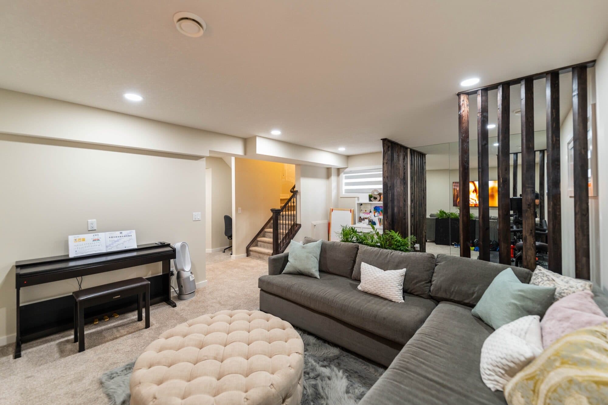 Basement rec room wide view with sectional sofa and slatted wood partition
