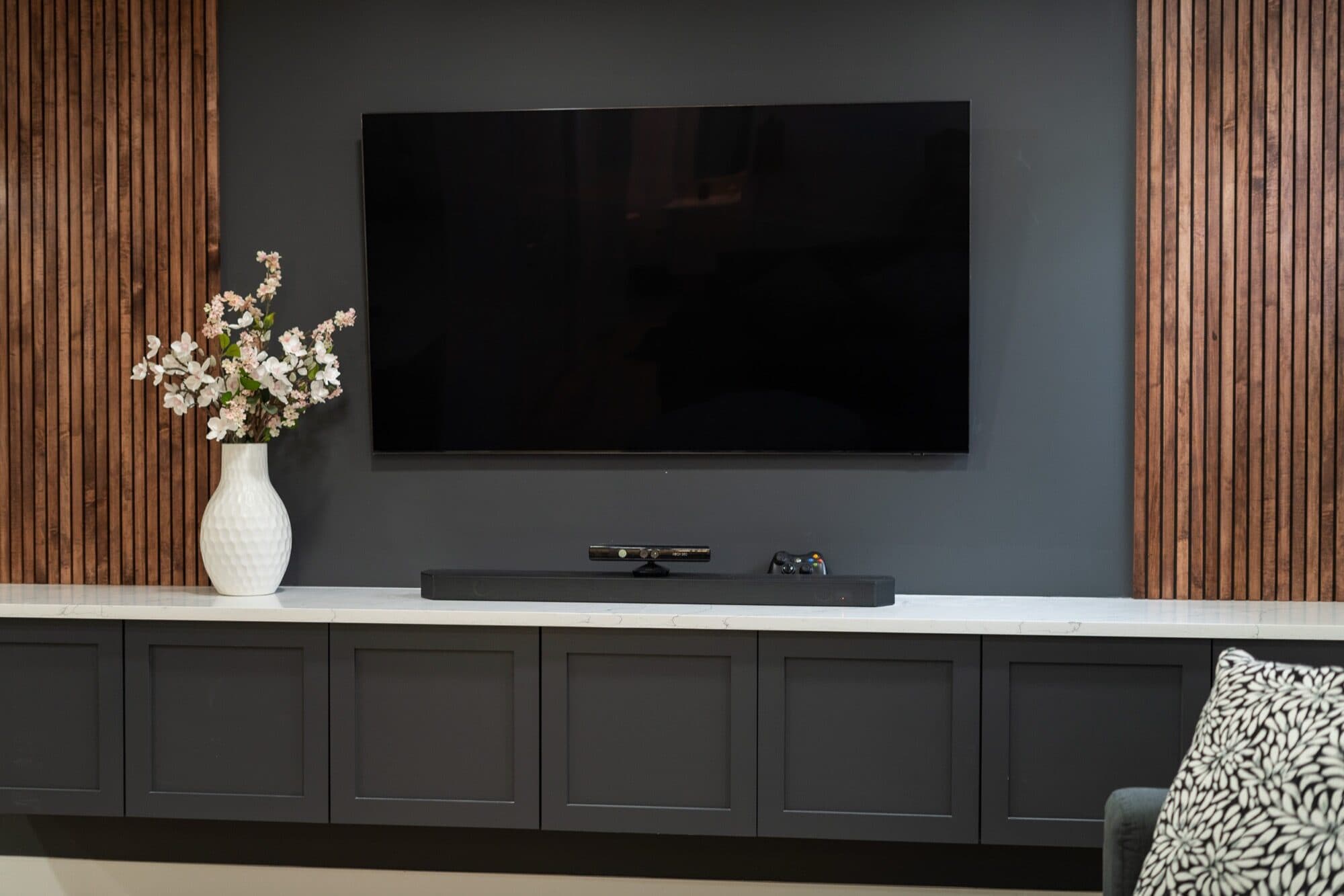 Basement dark feature wall with wood slats flanking a mounted TV